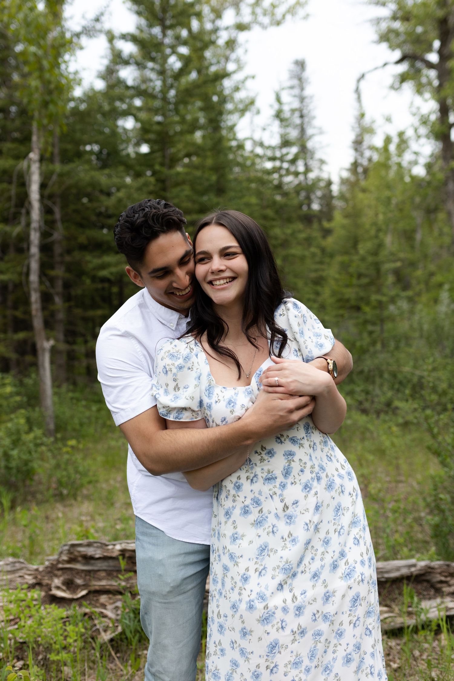 Romantic couple embracing in a sunlit forest setting.
