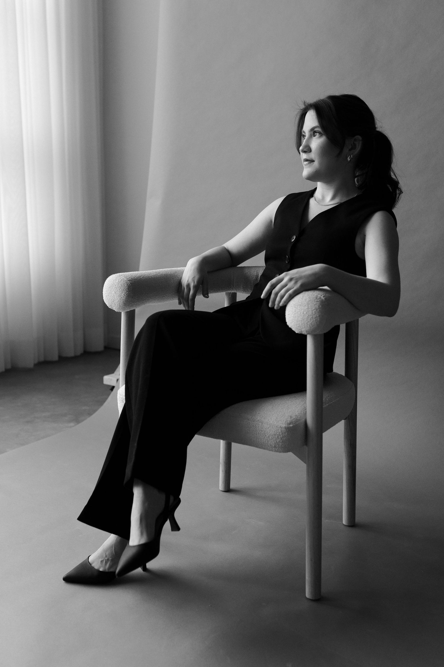 Black and white photos showing various seated poses in a minimalist chair against white curtains.