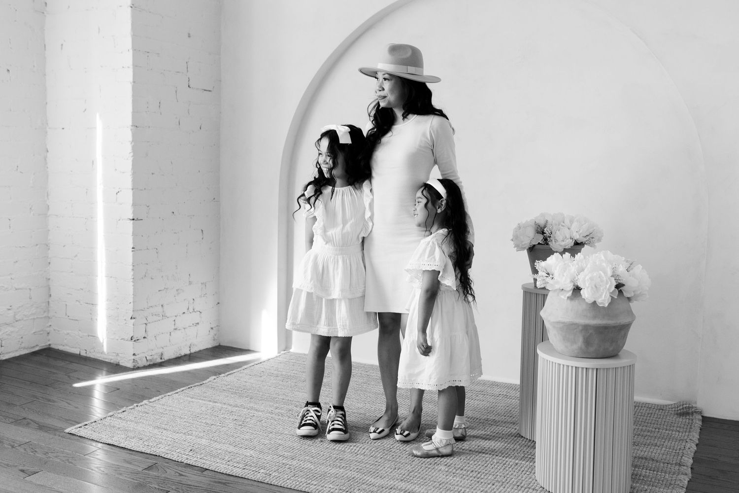 Black and white studio portraits showing playful interactions in white dresses against a minimalist backdrop.