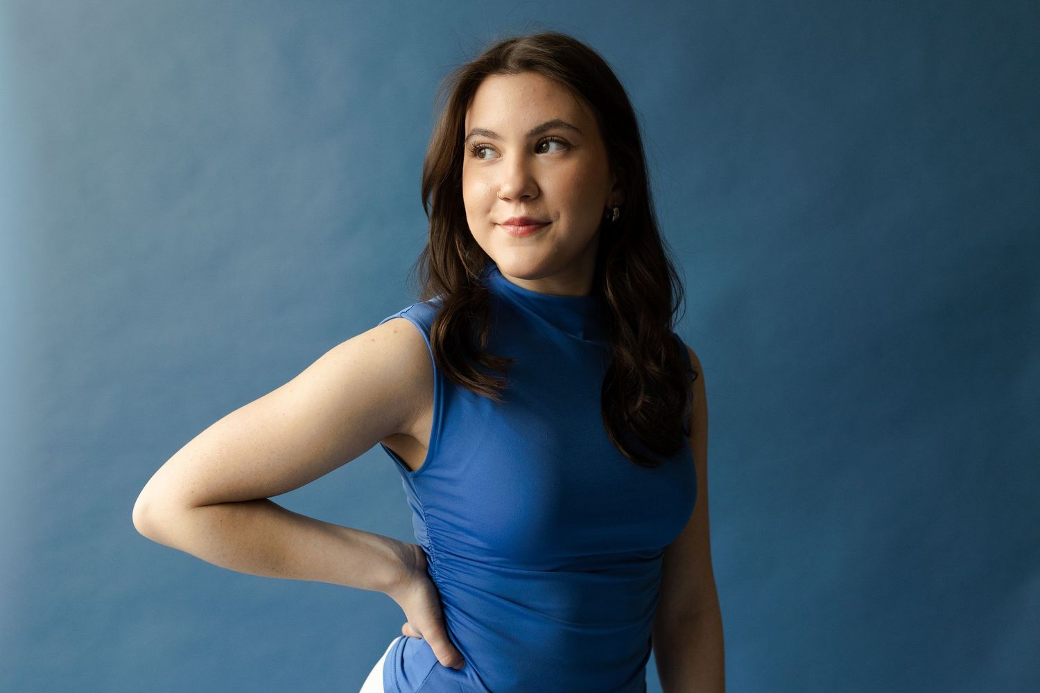 Athletic poses captured in a blue sleeveless top against a deep blue background.