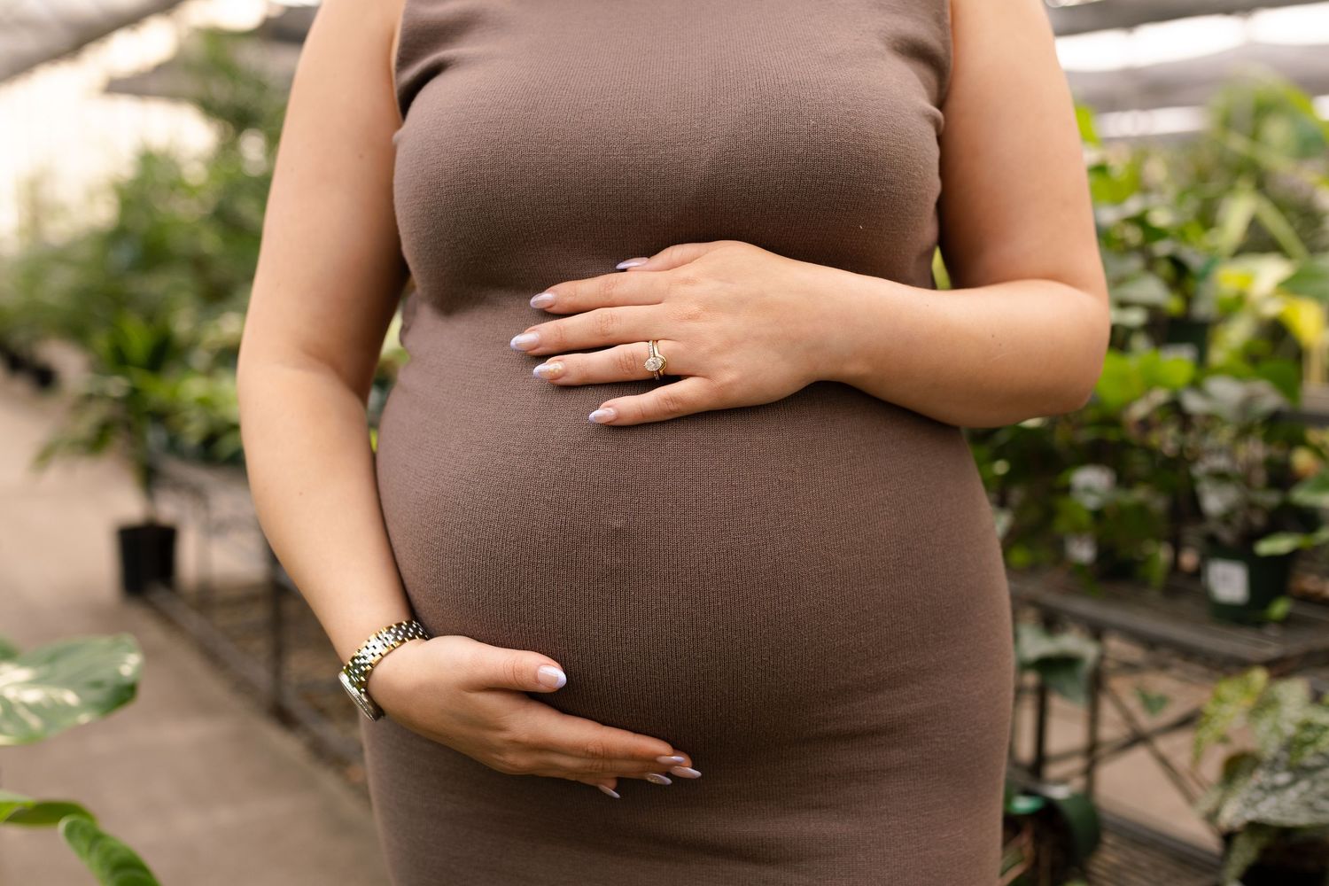 Close-up shots of brown maternity dress against greenhouse backdrop.