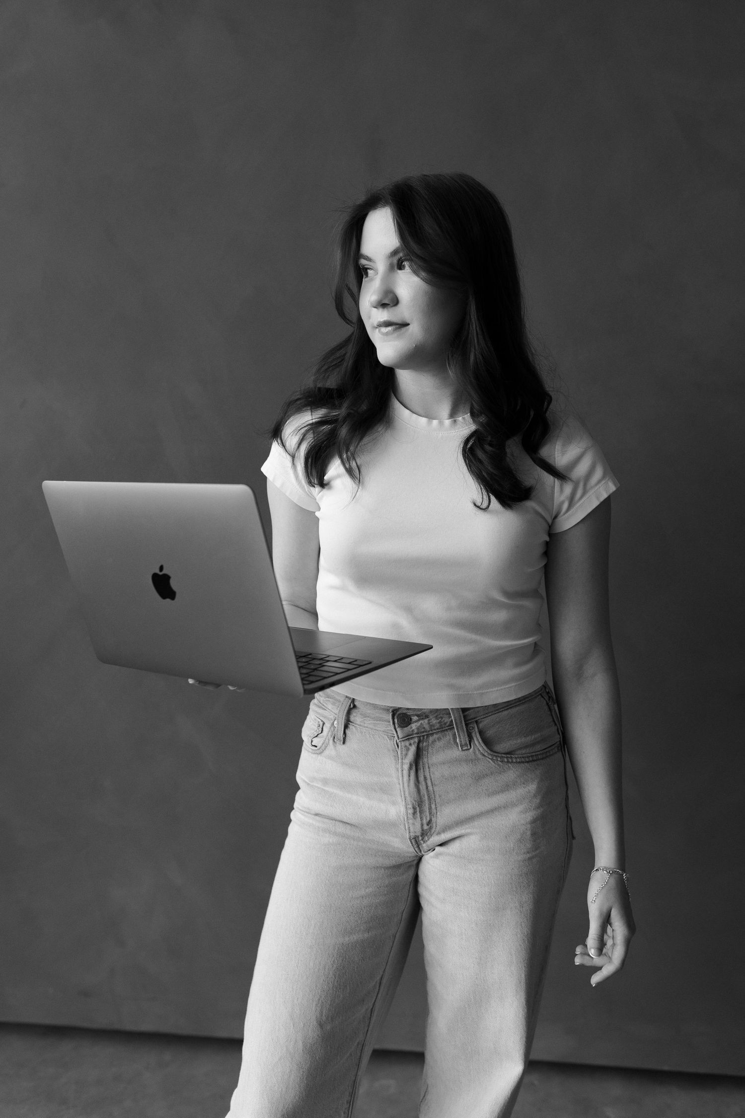 Modern lifestyle portrait of someone working on MacBook laptop wearing casual white t-shirt and jeans.