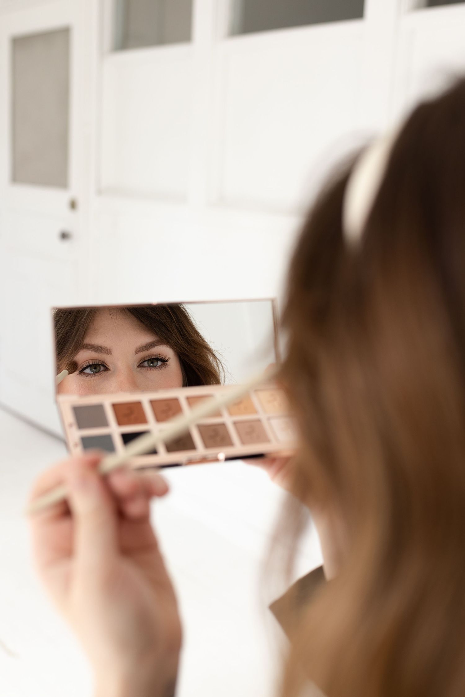 A close-up shot of someone looking at an eyeshadow palette in natural light.
