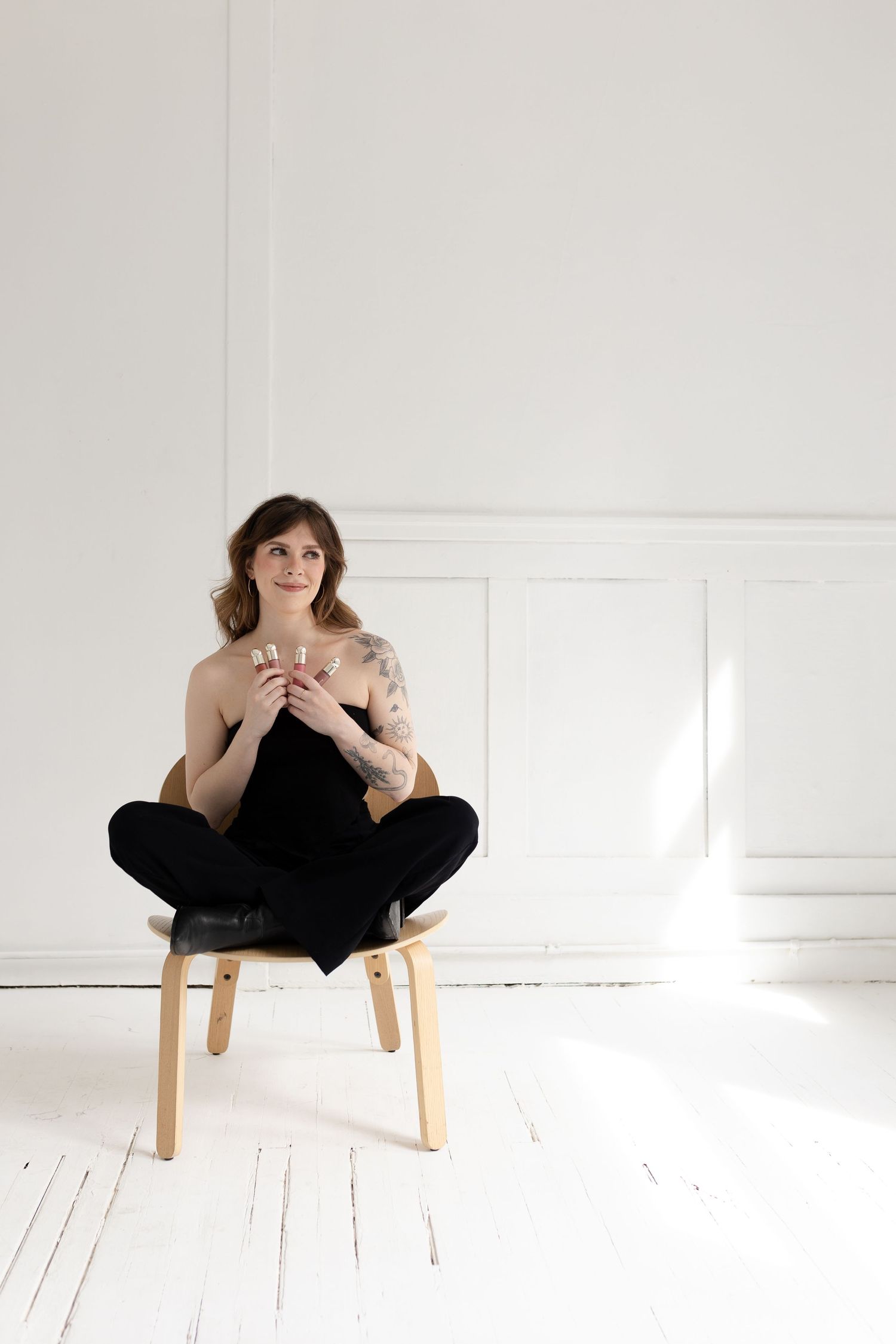 Artistic portrait series on wooden chair in minimalist white studio.