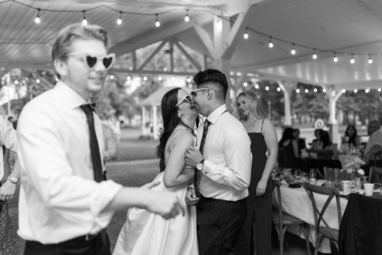 Wedding reception under string lights with guests dancing and celebrating.