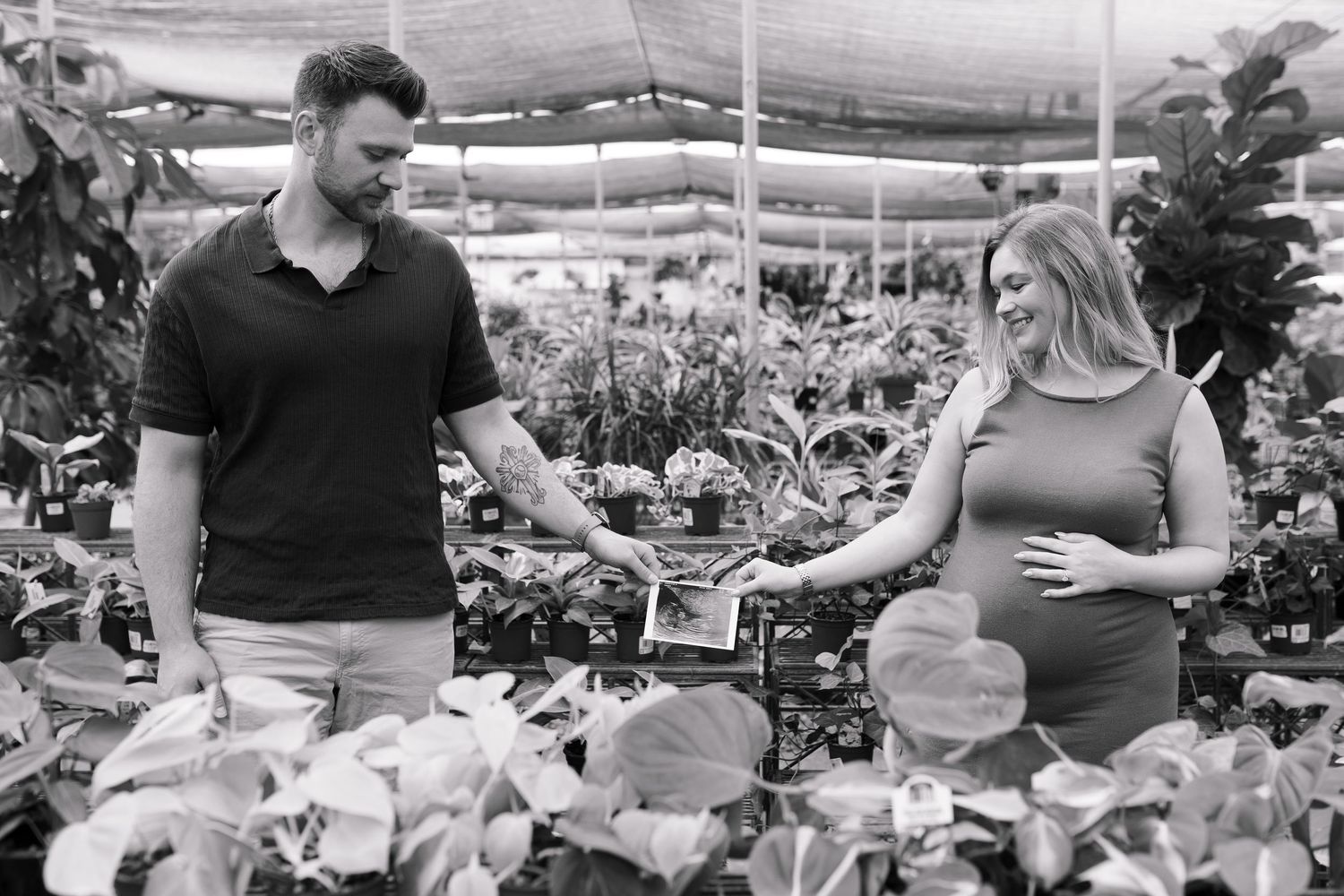 Black and white greenhouse maternity photos with hanging plants in background.