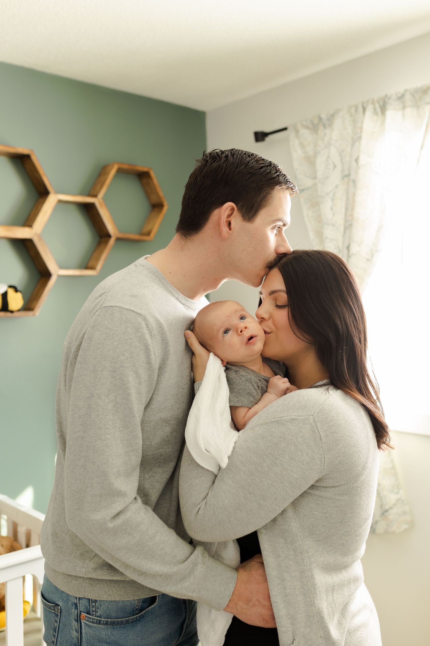 Family lifestyle photos in a nursery with mint green walls and honeycomb shelves.
