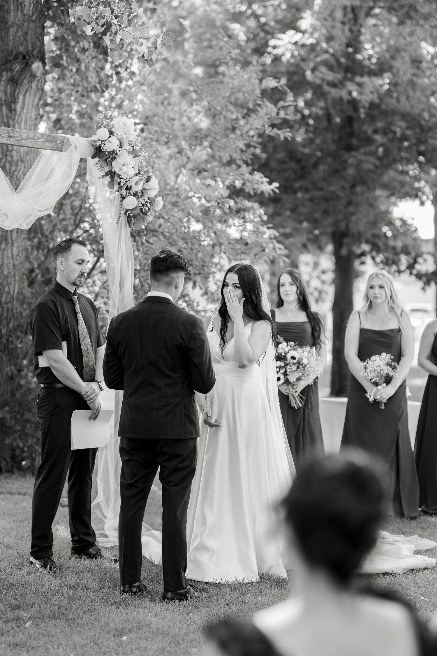 A series of black and white photos showing an outdoor wedding ceremony with people gathered under trees.