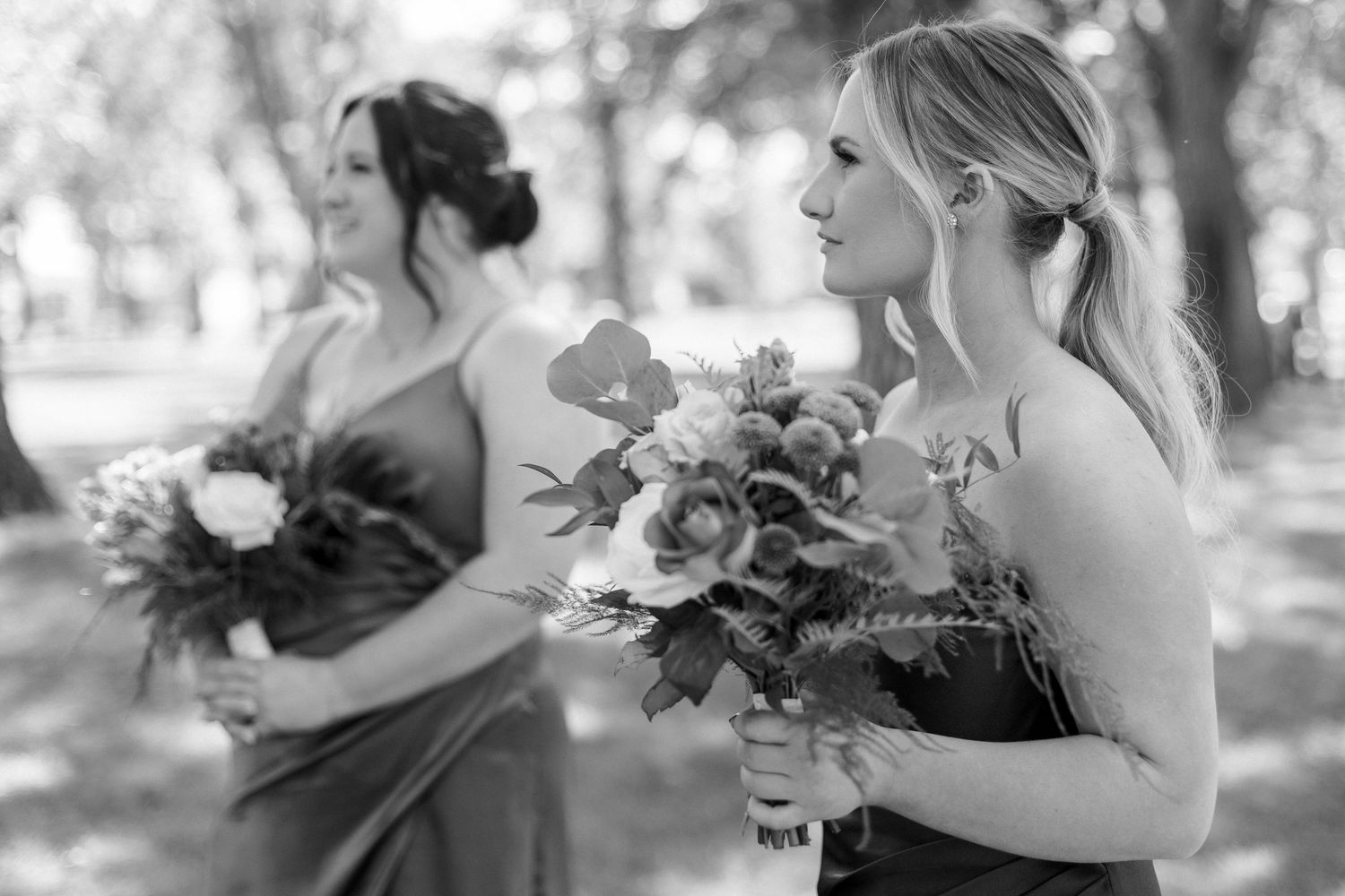 Black and white photo of wedding party members posing with bouquets.
