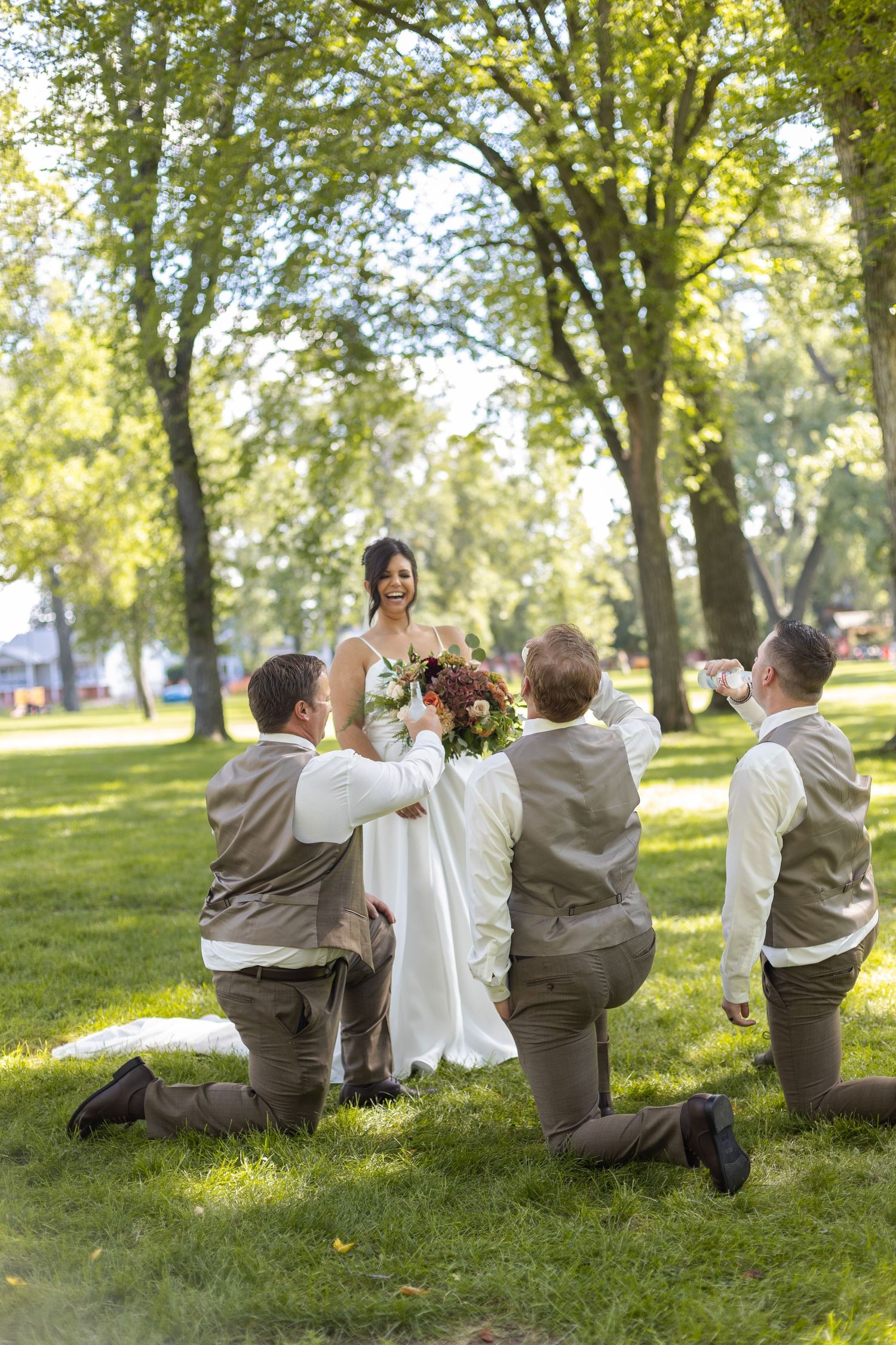 Wedding party members in brown suits pose playfully on grass under trees in a creative photo sequence.