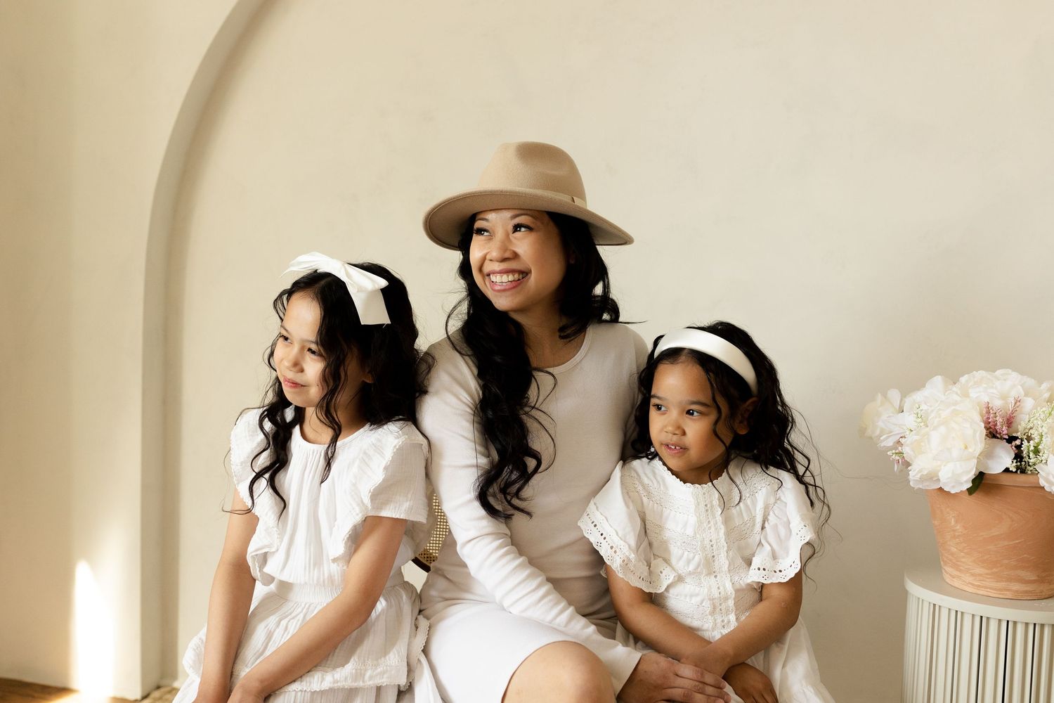 A series of warm-toned studio portraits showing tender moments in matching white dresses against a neutral backdrop.