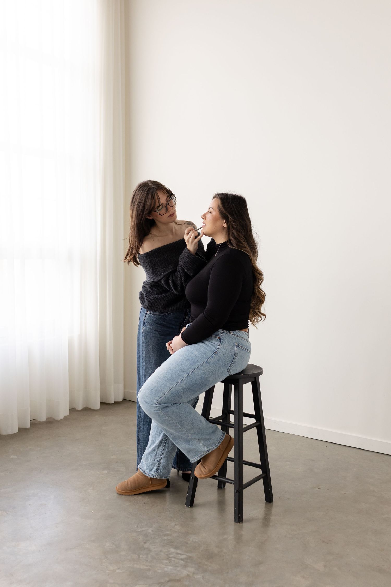 A series of artistic photos showing a person in jeans sitting on a dark stool against a white wall in different poses.