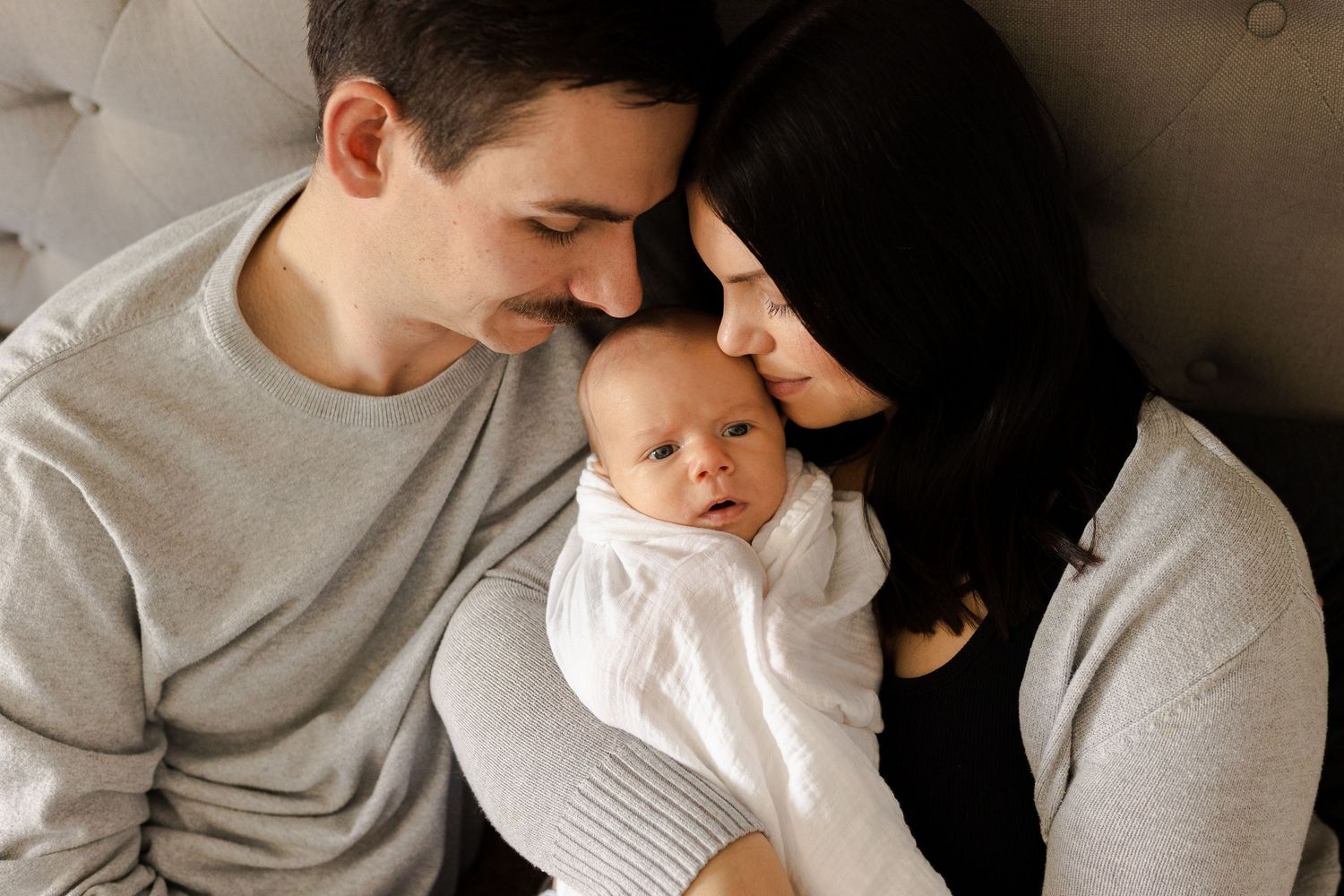 A series of intimate black and white photos showing tender moments between a parent and baby in casual attire.