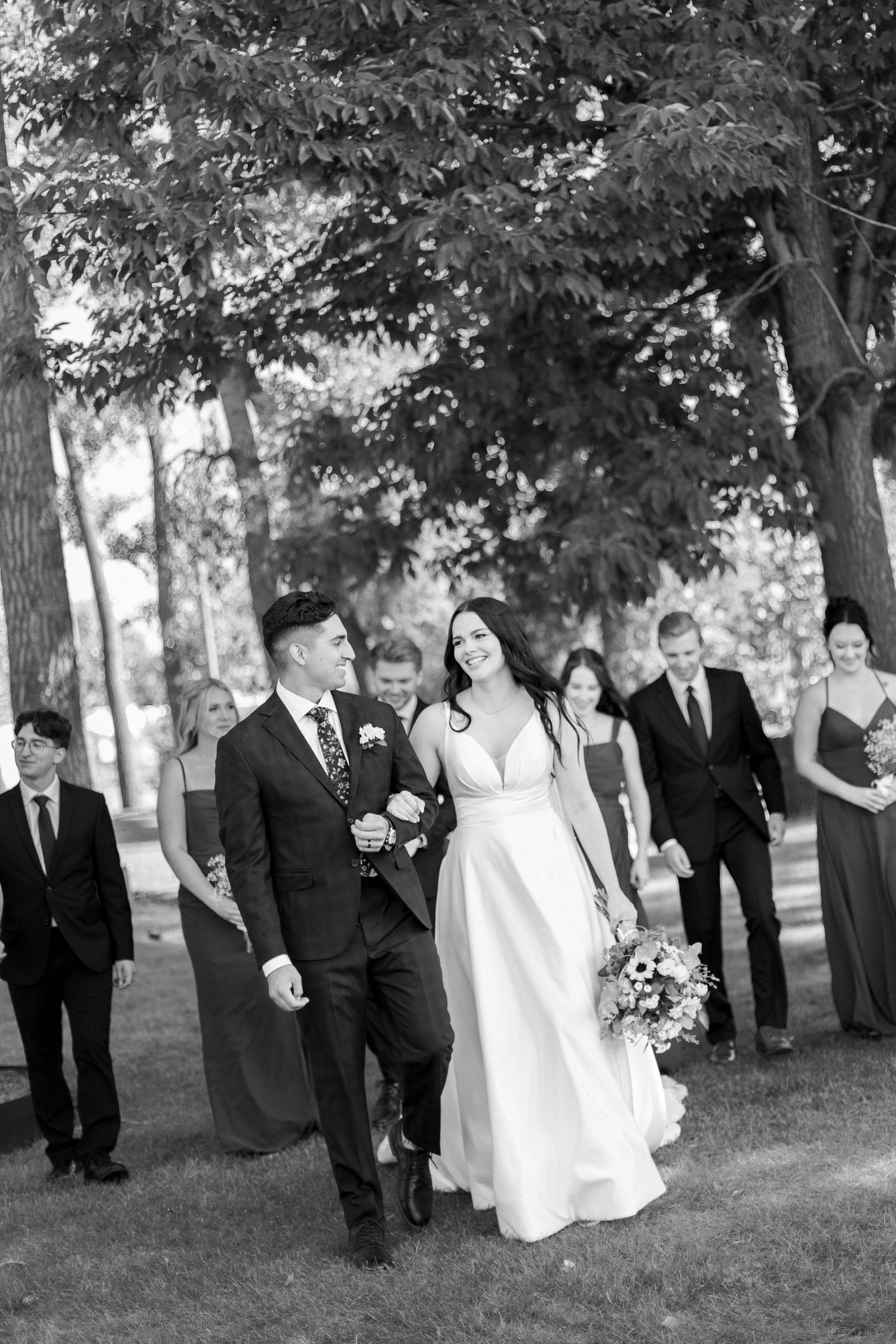 Black and white wedding party photo sequence showing joyful moments between couples and attendants in an outdoor setting.