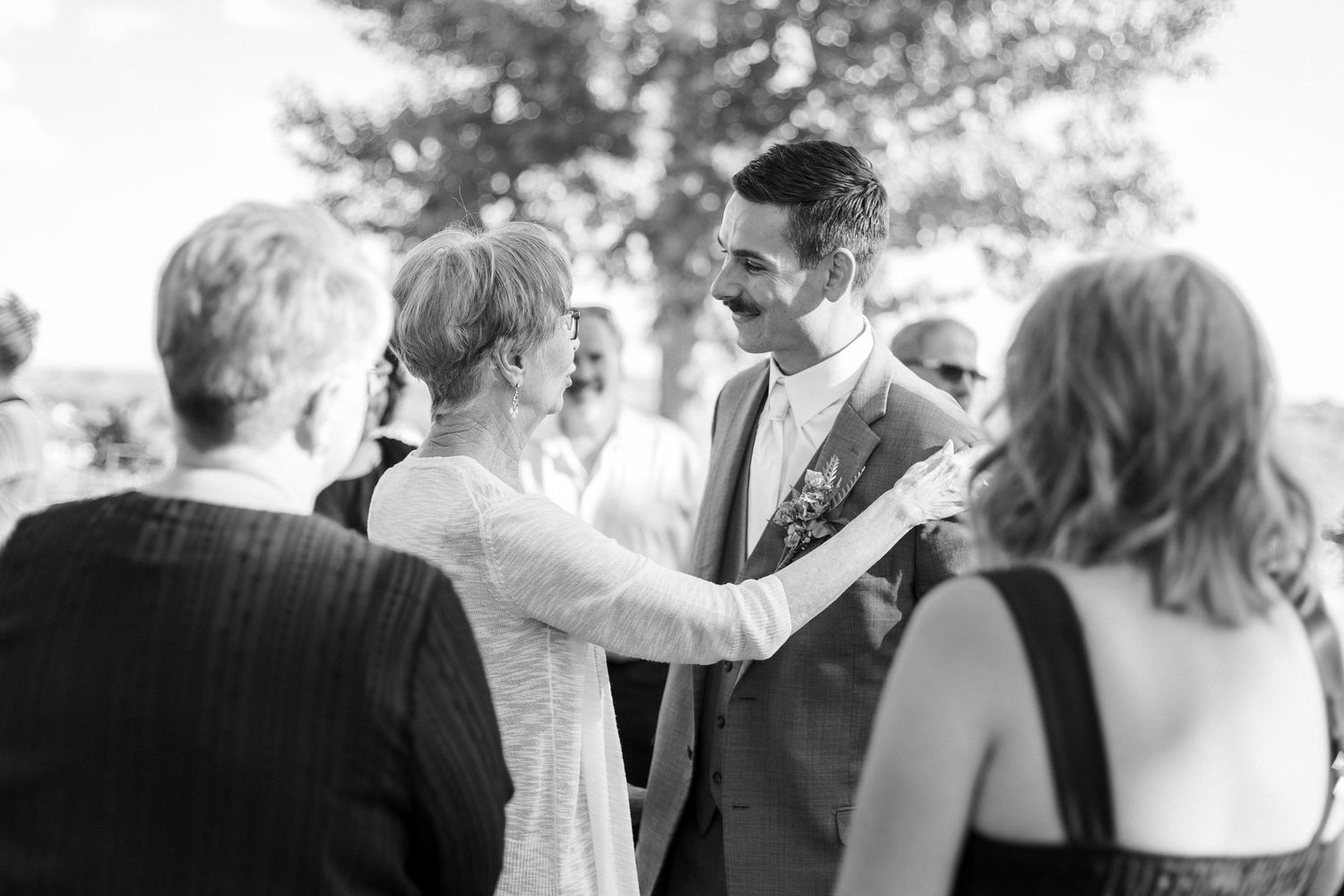 Black and white photo of guests gathered outdoors at a wedding celebration.