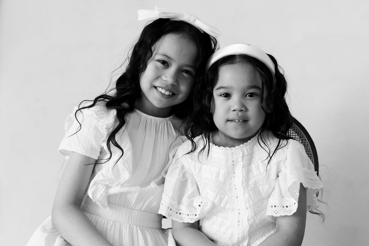 Black and white studio portraits showing tender embraces in matching white outfits.