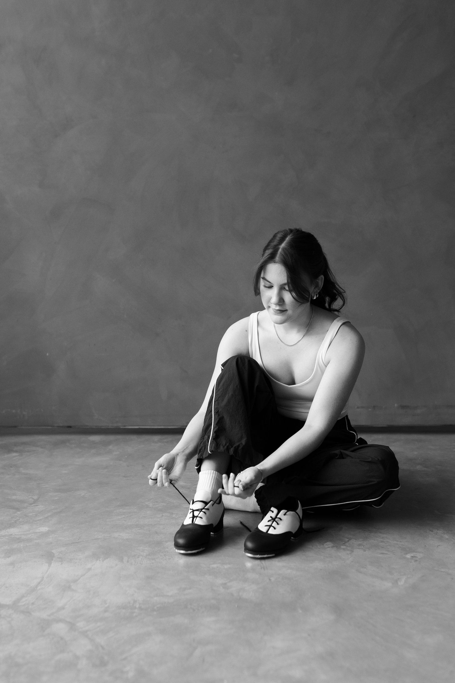 Black and white photo series showing someone tying shoelaces while sitting on the floor.