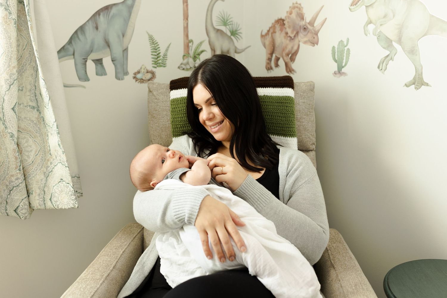 Family lifestyle photos in a nursery with animal artwork and white curtains.