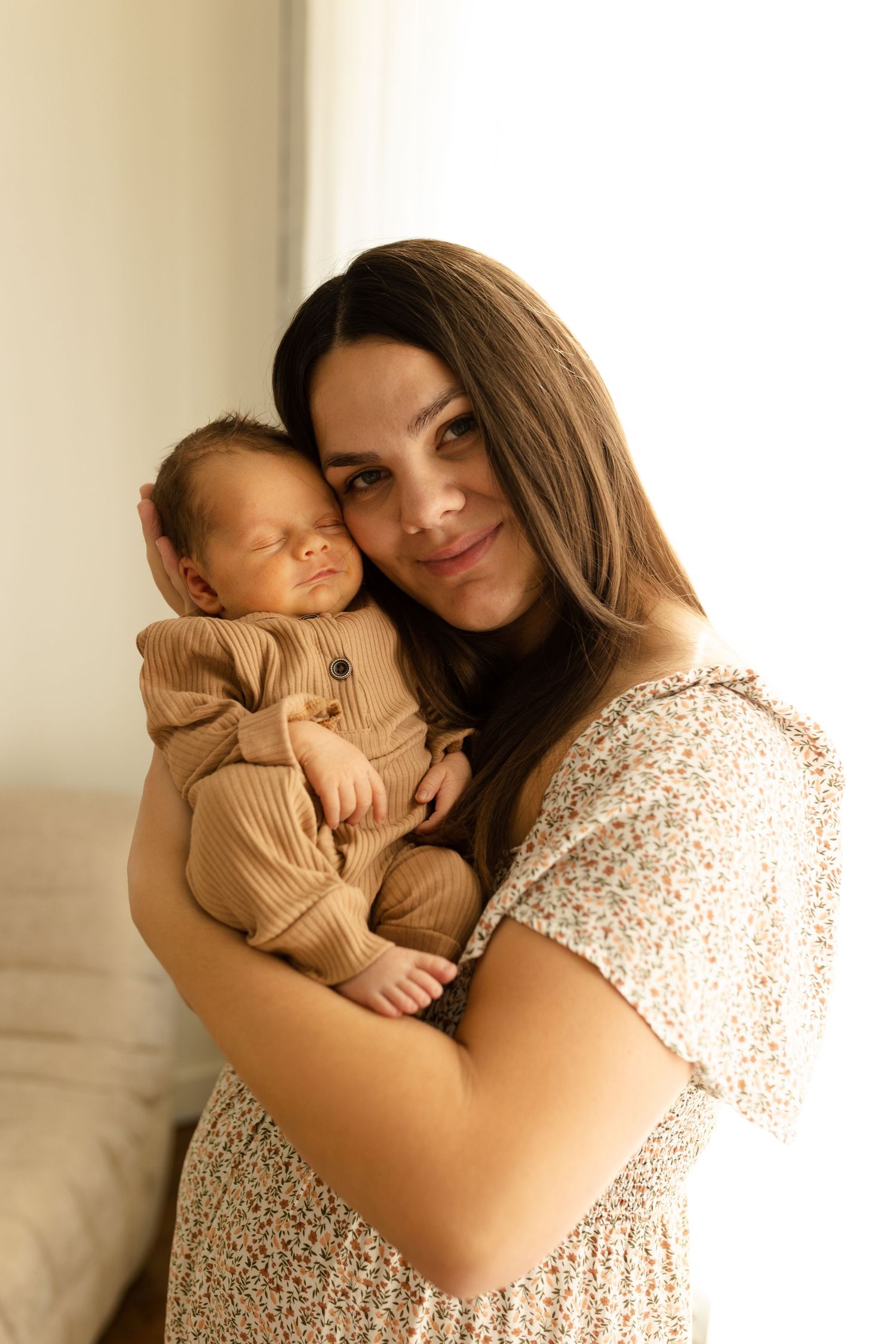 Mother and baby share intimate cuddles in soft natural window light.