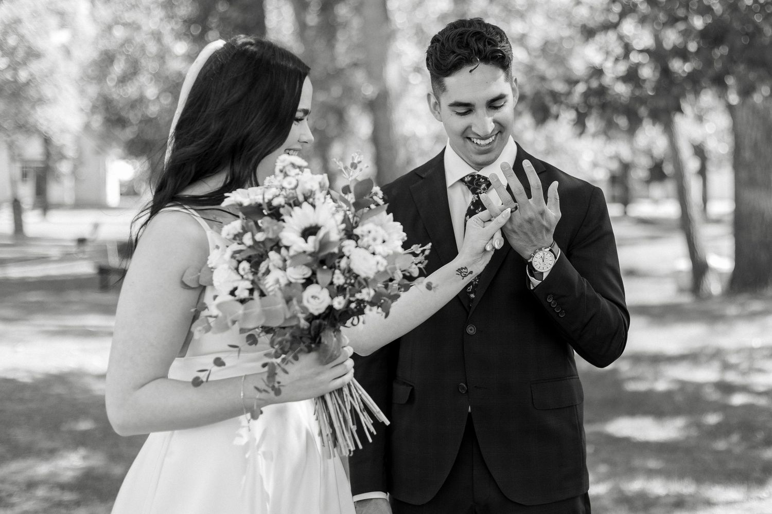 A couple shares an emotional first look moment in a park setting with a beautiful bridal bouquet of flowers.