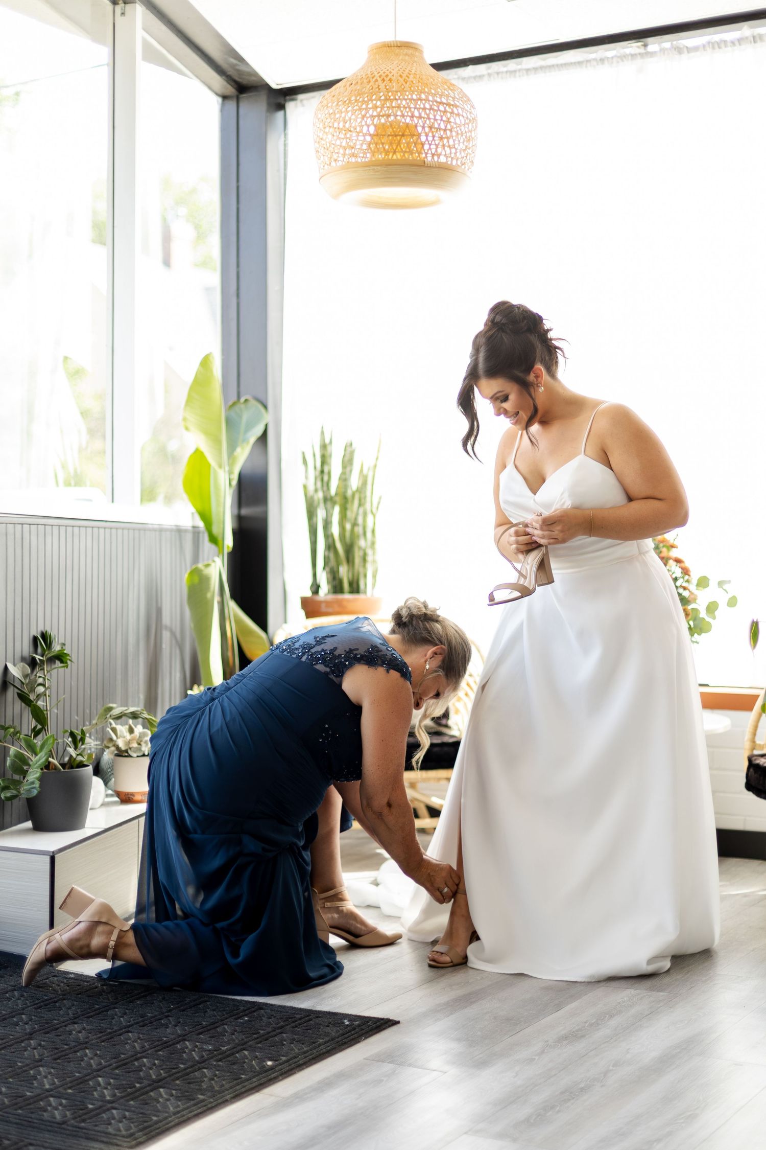 A series of photos showing a person in a white dress getting help with shoes while sitting in a bright modern room.