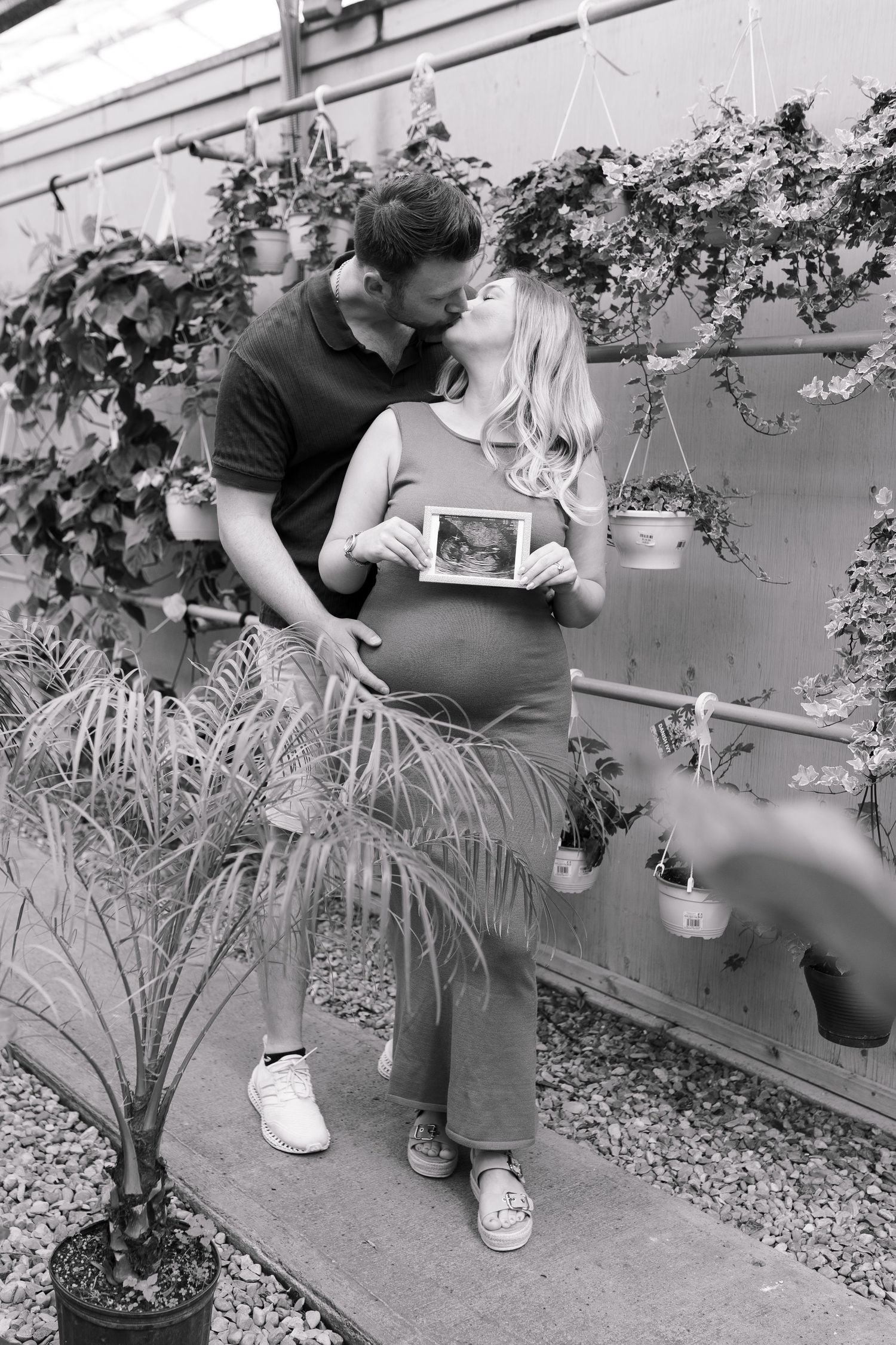 Maternity photoshoot in black and white showing couple posing with ultrasound photo.