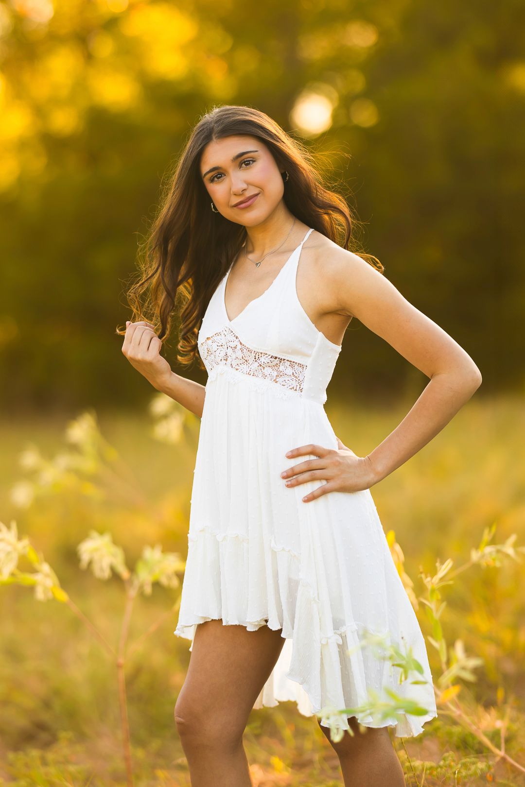 A white lace dress flows gracefully in a golden sunlit field during sunset.