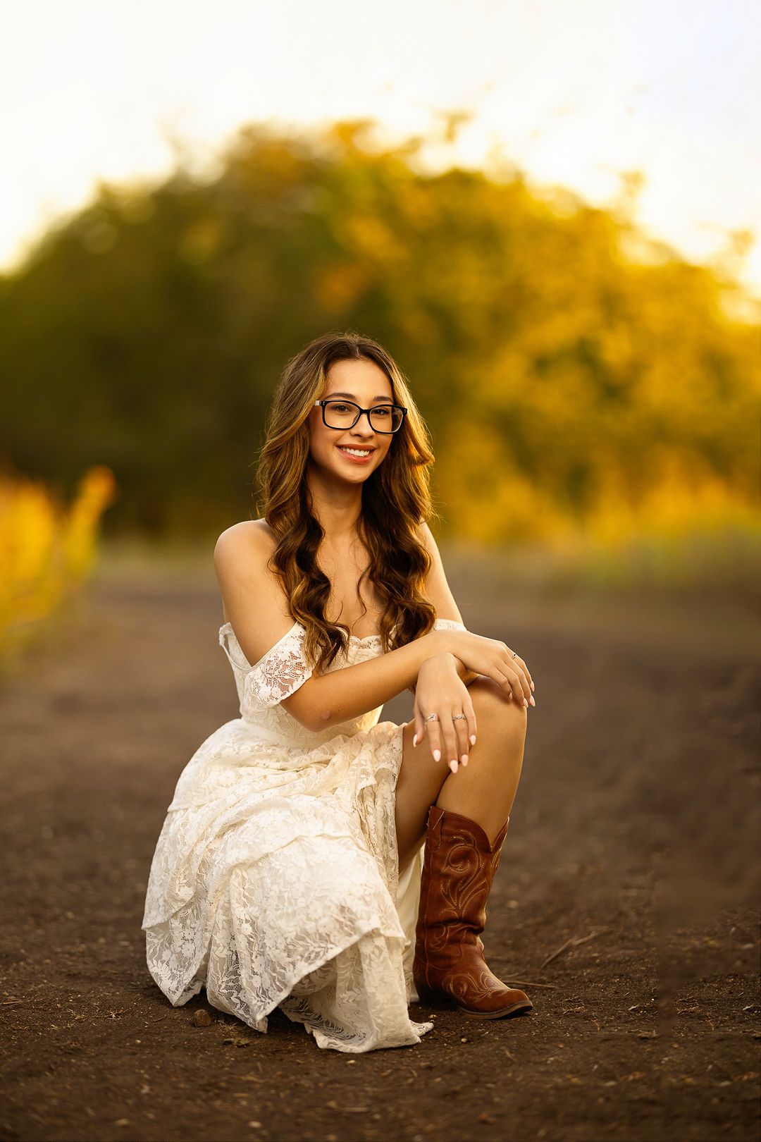 Rustic portrait with cowboy boots and white lace dress during golden hour.