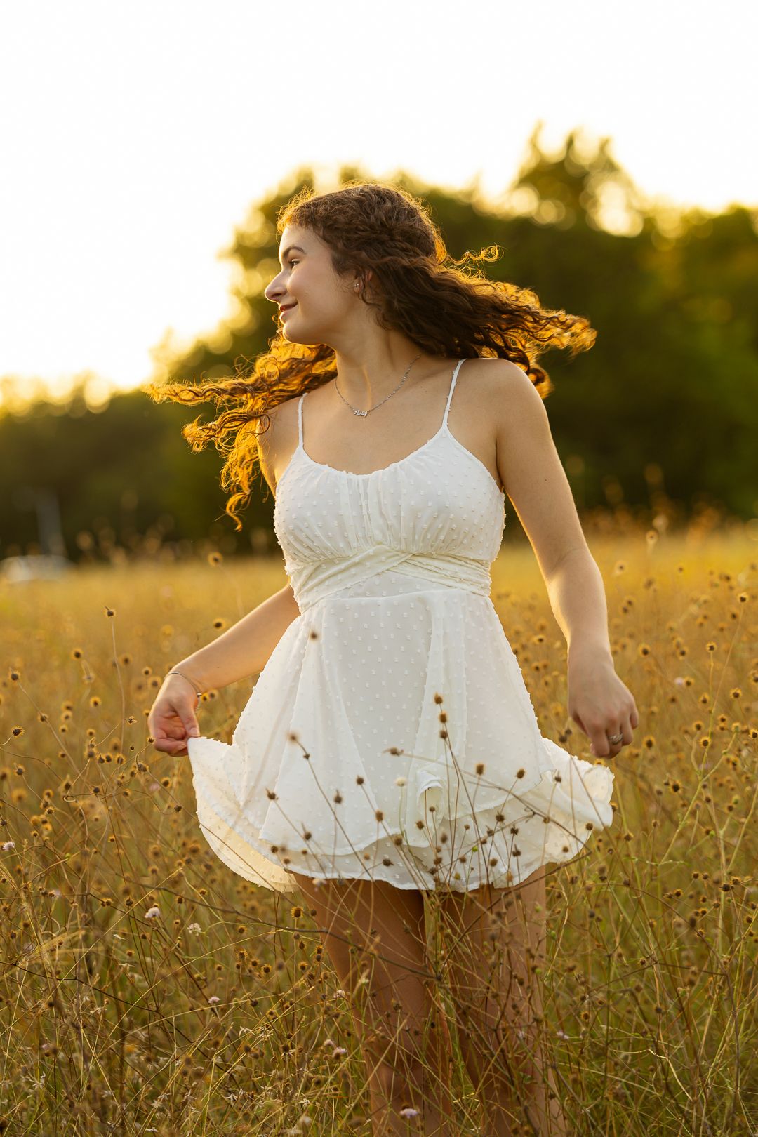 A person in a white sundress twirls joyfully in a golden sunlit meadow at sunset.