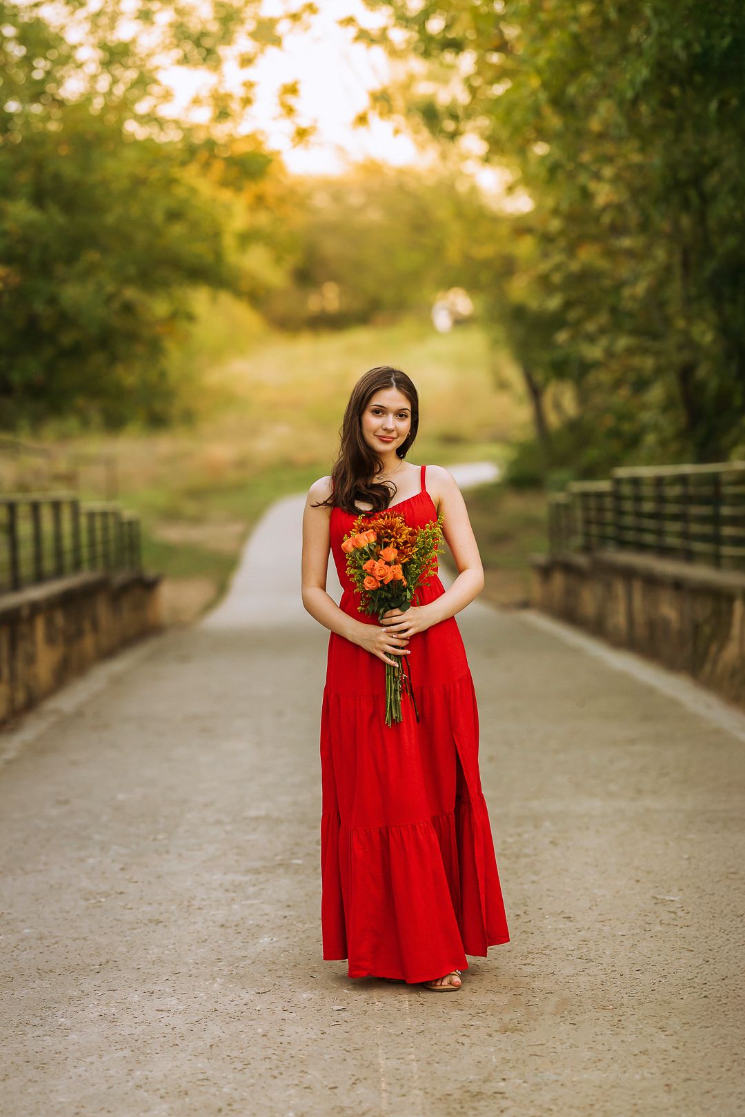 Portrait session on a rustic bridge path wearing a flowing red dress.