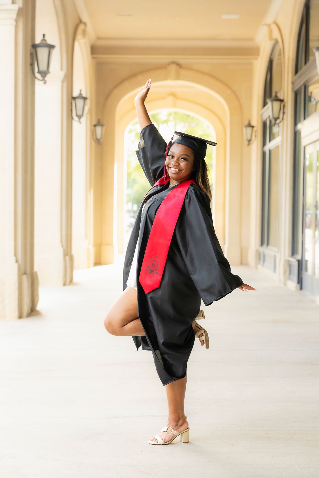 Graduation photos featuring black gown and red tie in classical architecture setting.