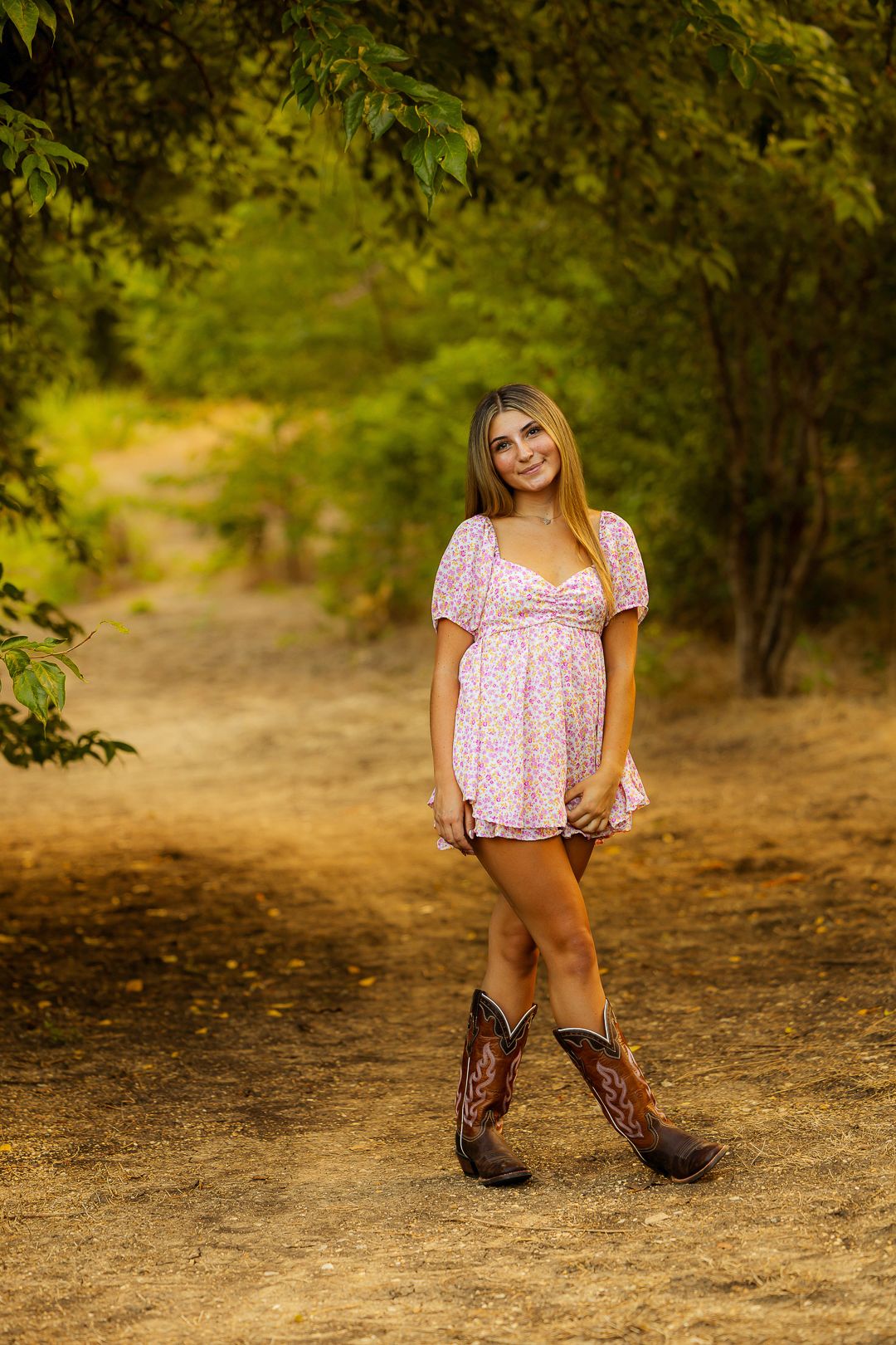 Outdoor fashion sequence with pink top and western boots on dirt path.