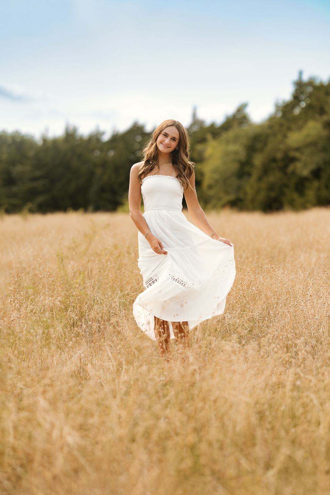 Woman in flowing white dress twirls joyfully through a golden wheat field on a sunny summer day.