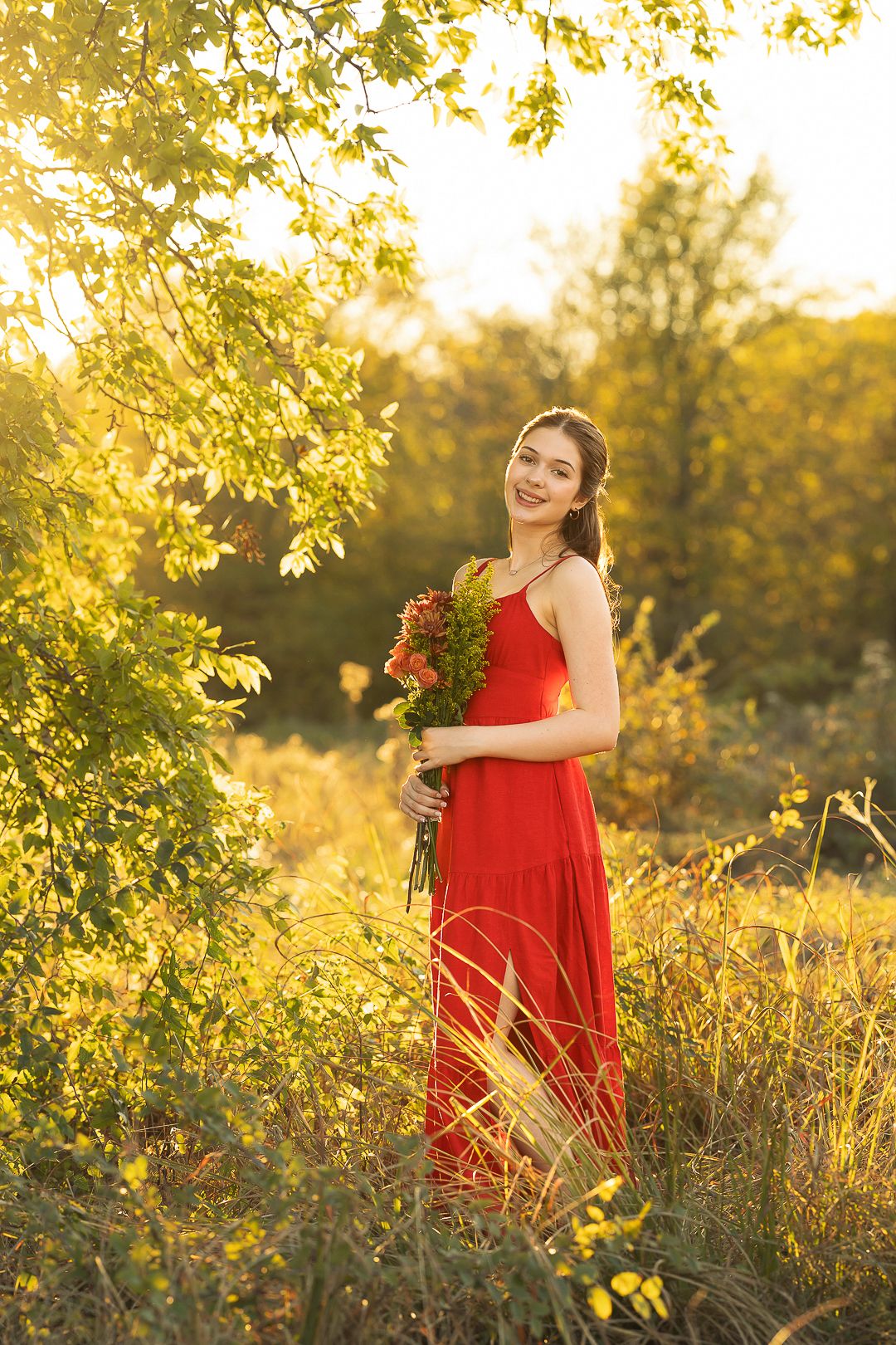 Red dress photoshoot in a sun-drenched field during golden hour.