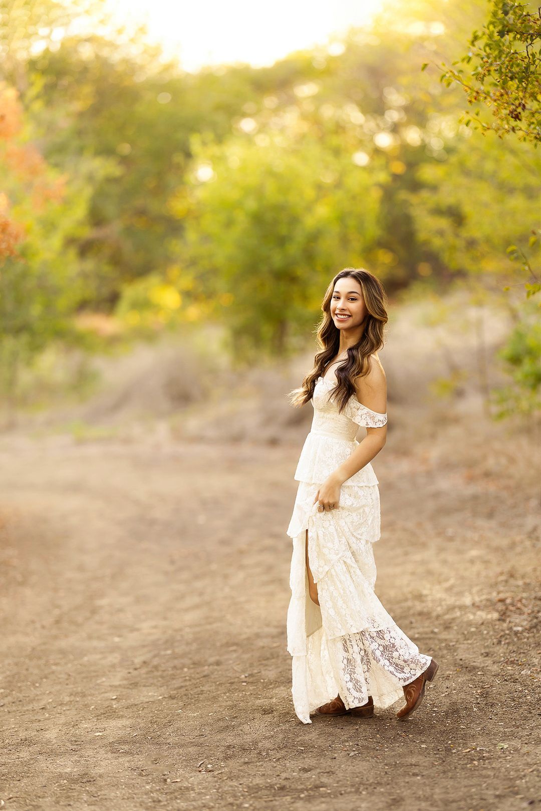 Flowing white lace dress captured in motion during sunset in a rustic outdoor setting.