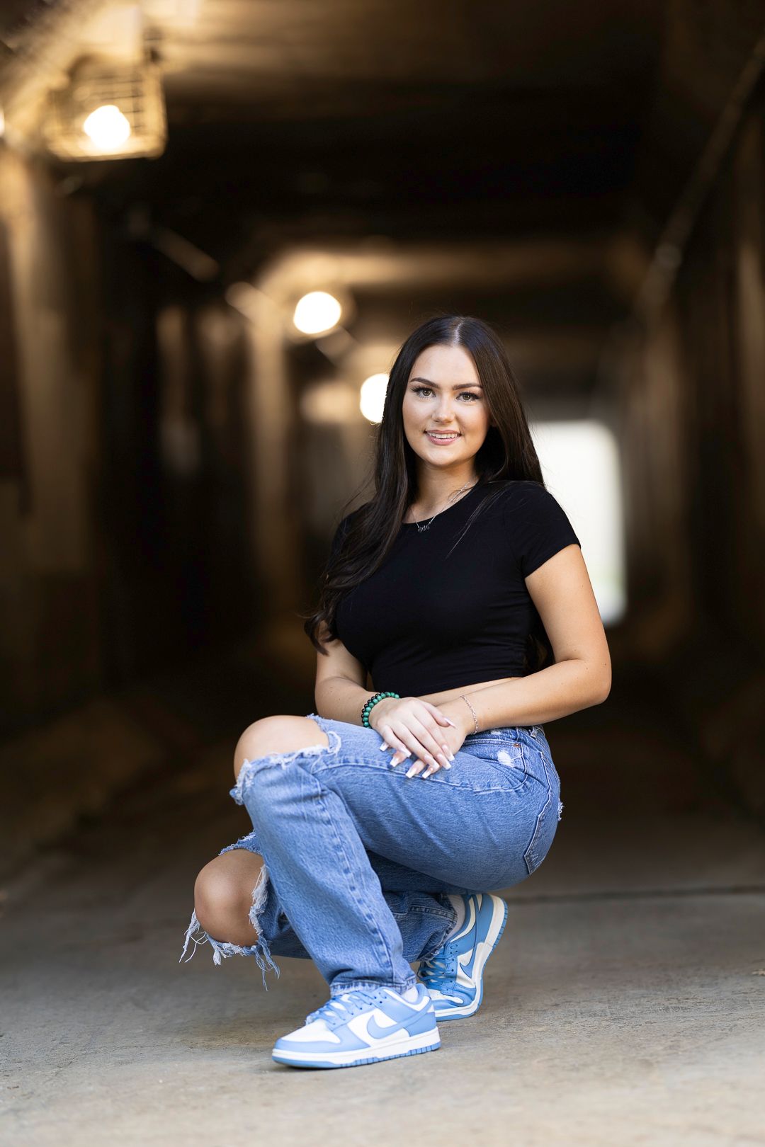 Casual black top and distressed jeans photographed in moody urban setting.