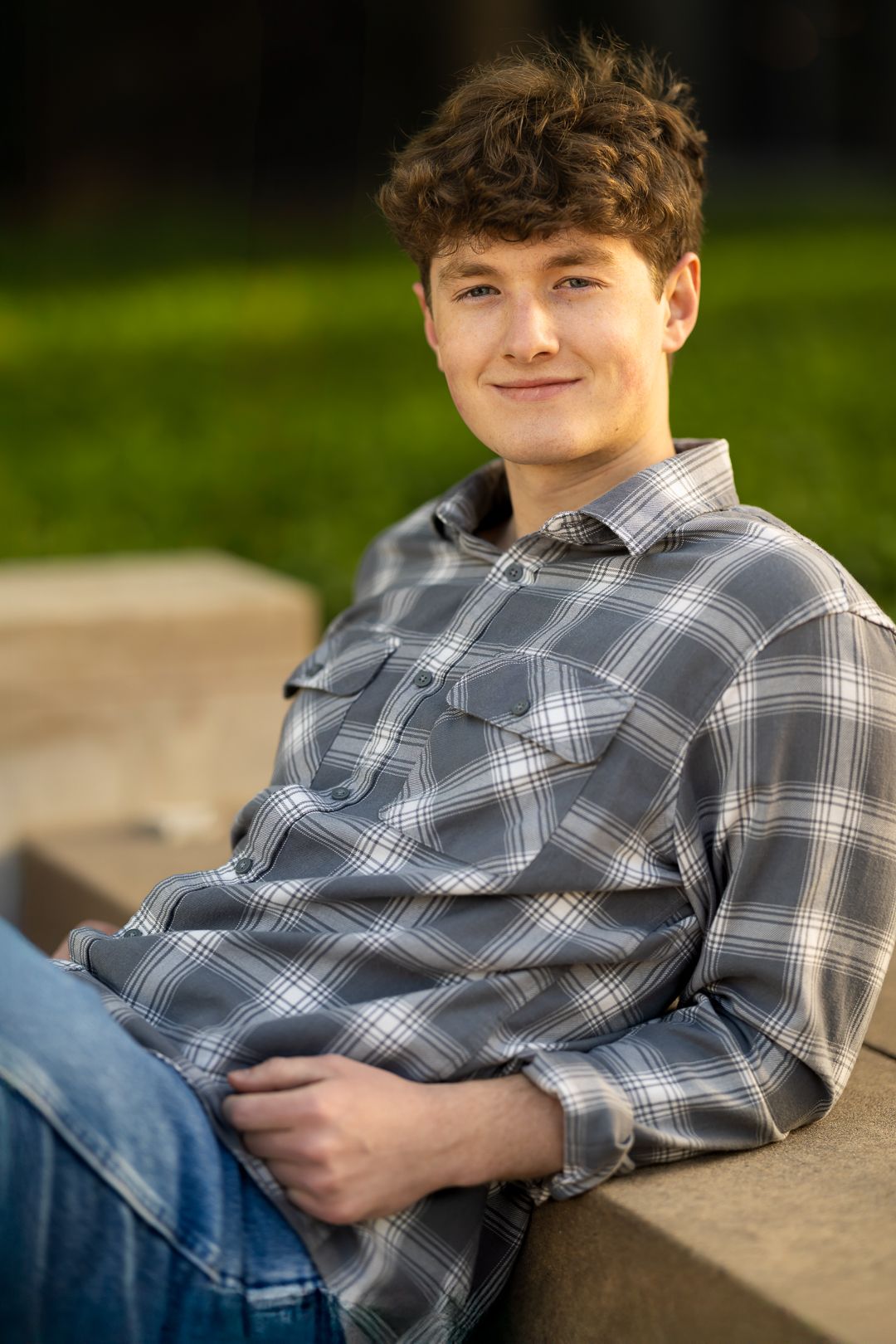 A series of casual outdoor portrait photos showing someone in a gray plaid shirt and jeans sitting on concrete steps.