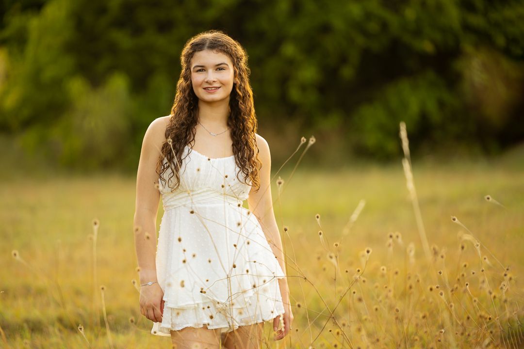 A person in a white dress stands in a golden field at sunset, creating a dreamy summer atmosphere.