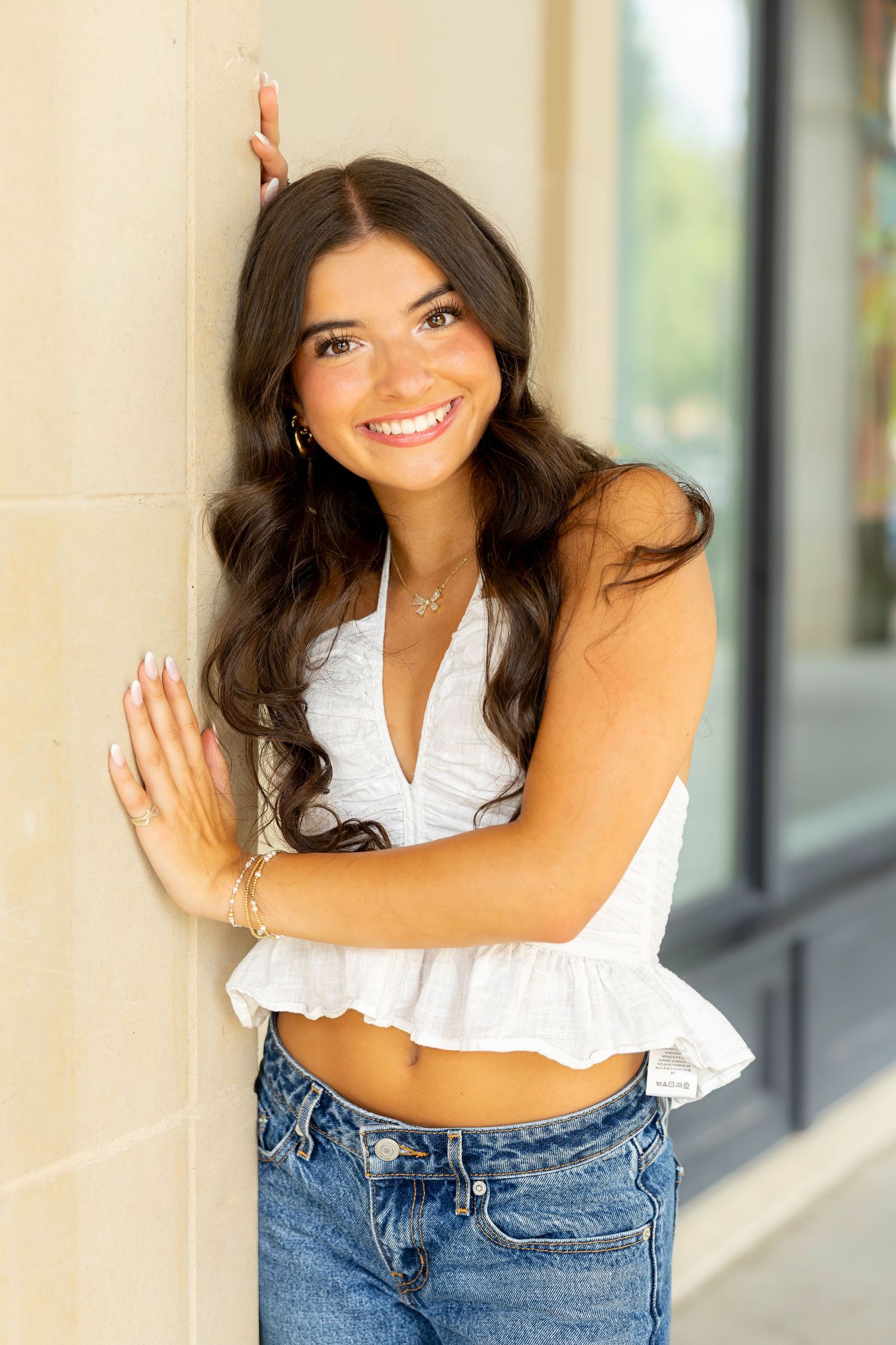 Summer fashion portrait with white crop top and denim against architectural backdrop.
