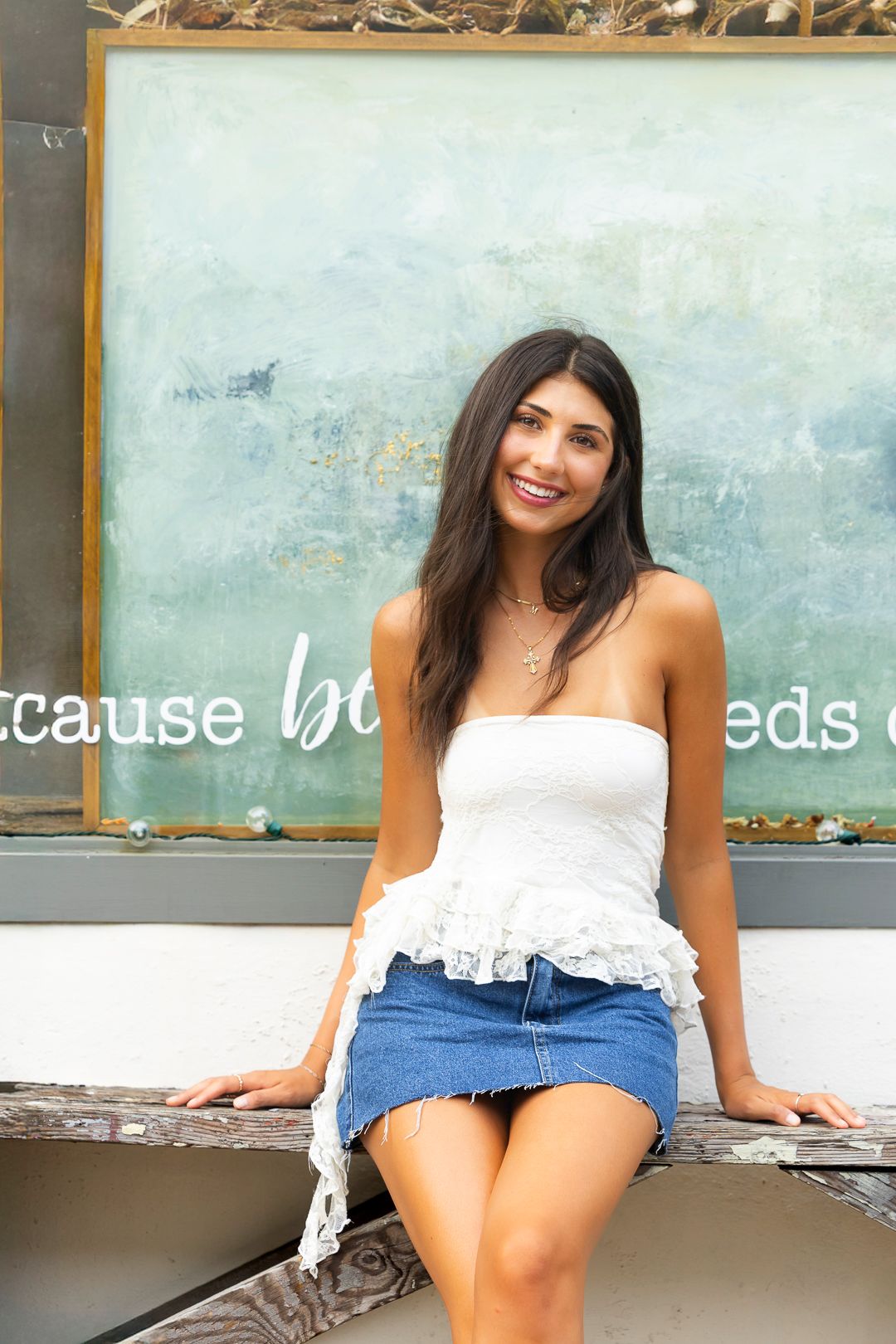 Casual summer fashion poses on a bench with rustic storefront backdrop.