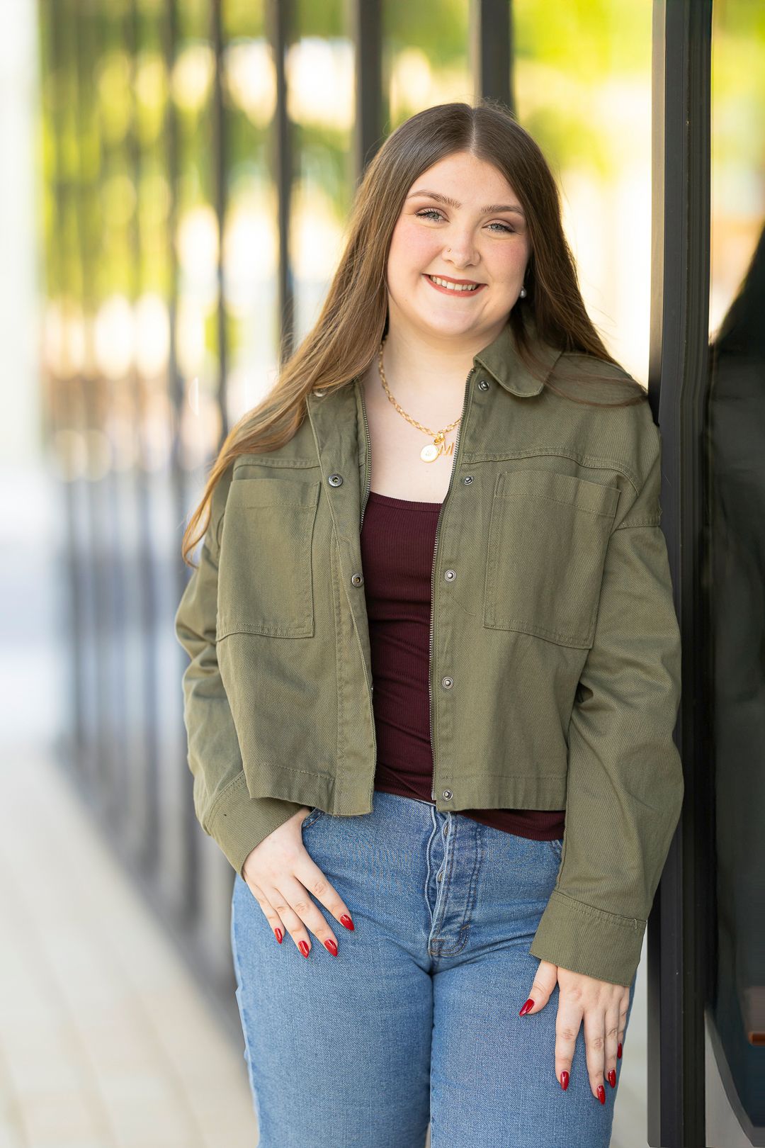 Casual outfit featuring olive green jacket and jeans against white background.