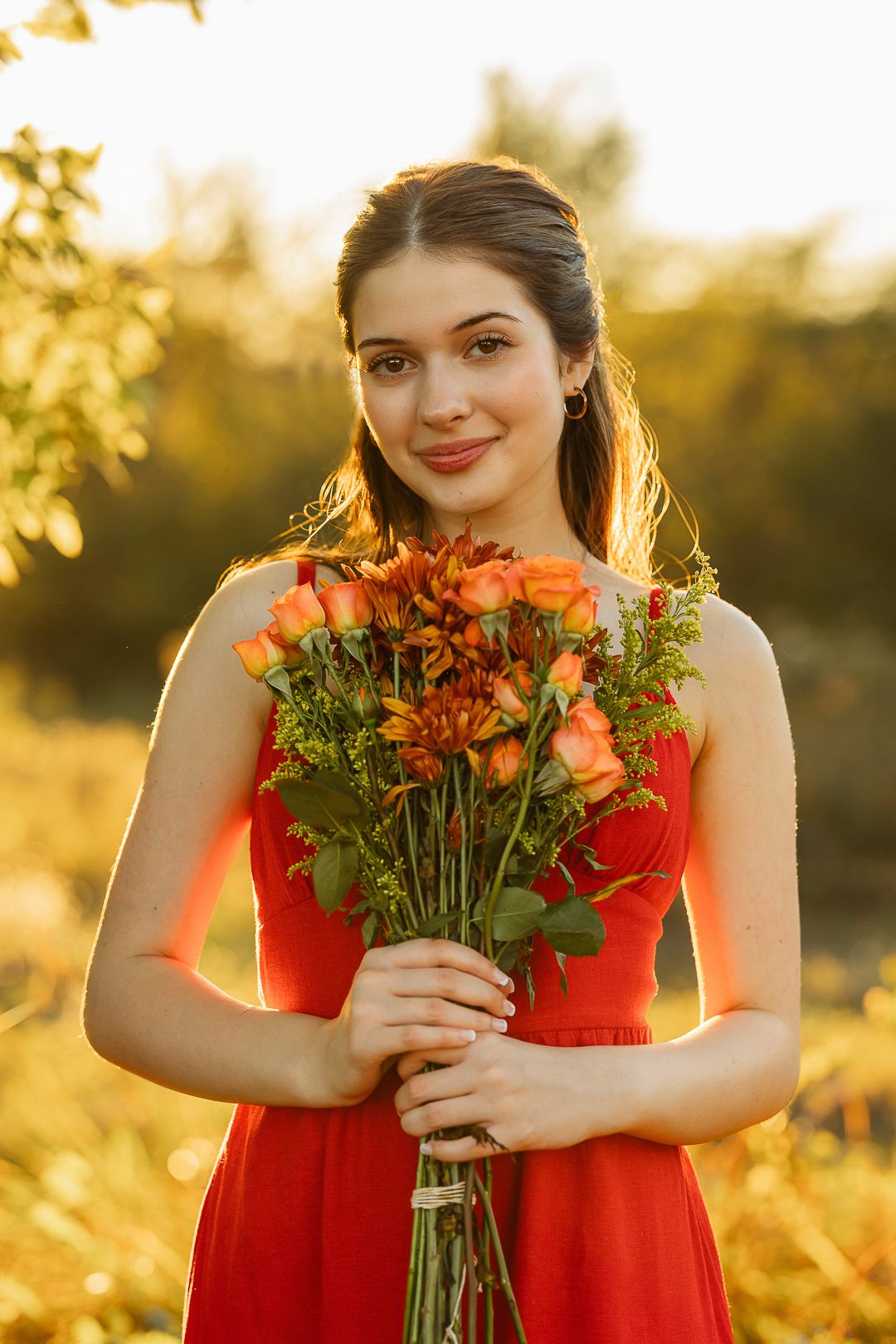 Portrait session with orange flowers against golden sunset light.