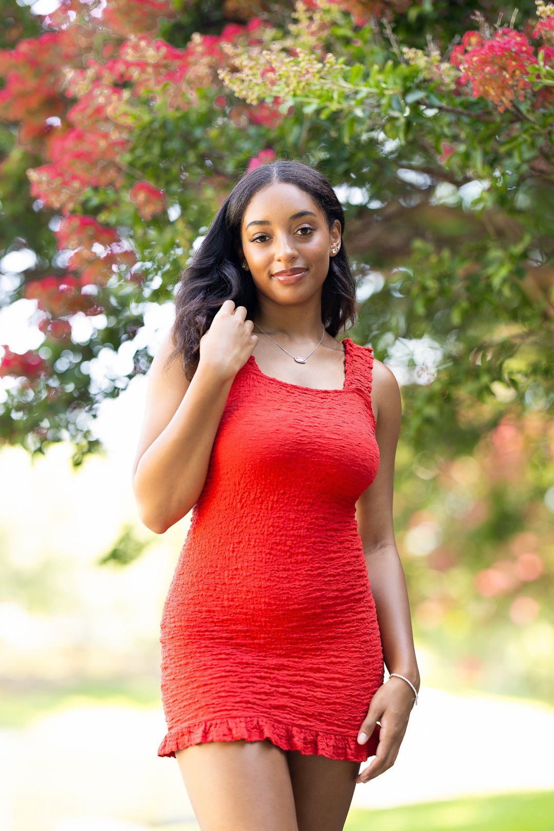 Summer fashion shoot with a red smocked top against blooming pink flowers.