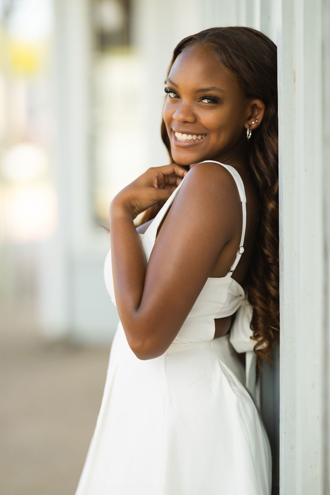 A series of four portraits showing someone in a white sleeveless dress posing against a light-colored wall.