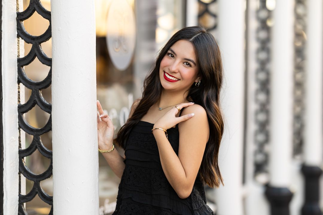 Woman in black dress smiling while holding white flag outdoors.