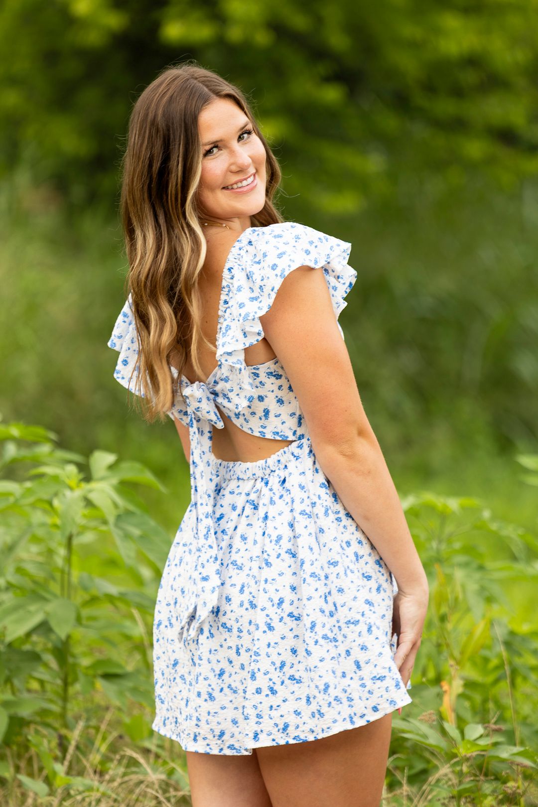 Summer portrait session in a floral blue and white top against lush green foliage.