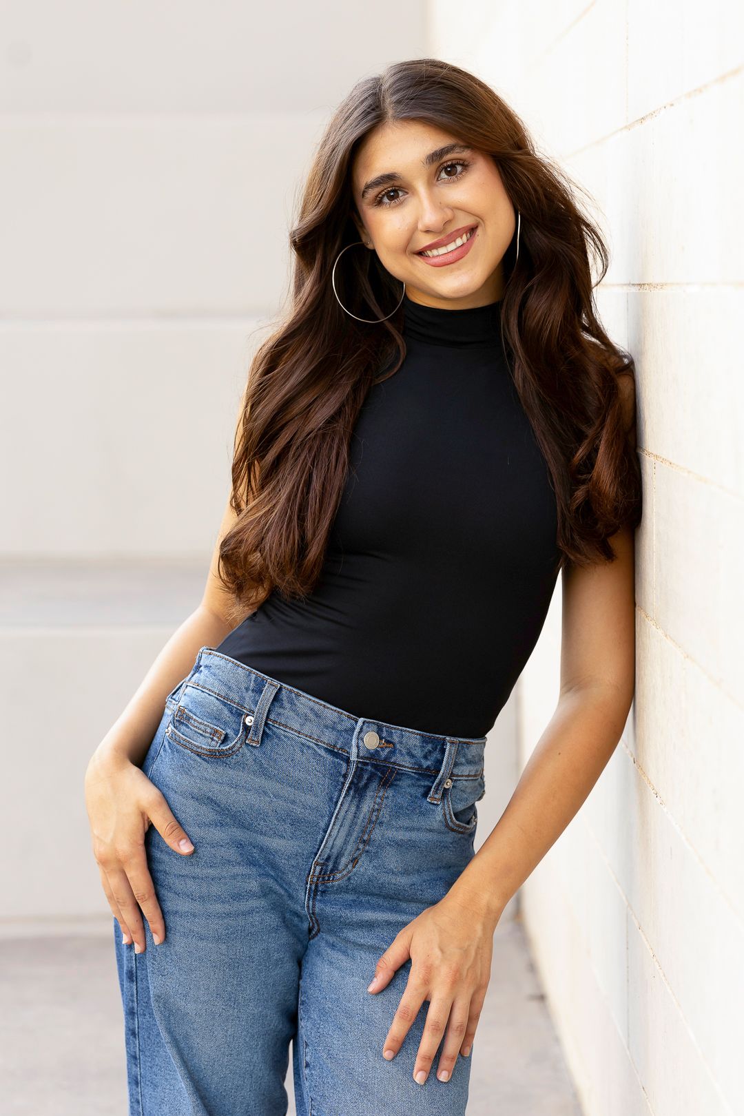Studio portraits showcasing casual denim and black top combination against white background.