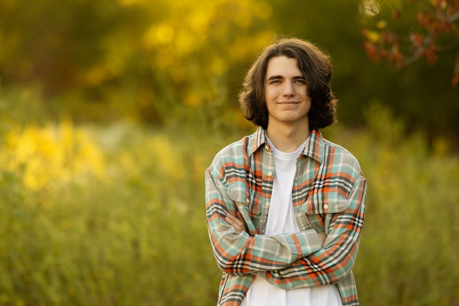 Person in plaid shirt posing outdoors against golden sunset field with natural lighting.