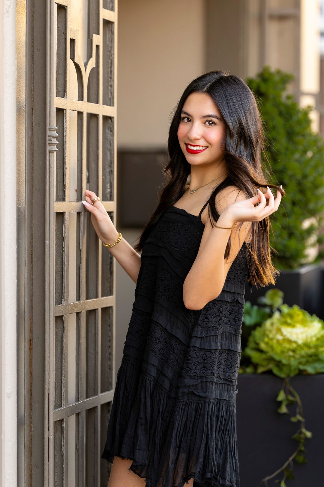 Person in black dress poses elegantly by window frames.