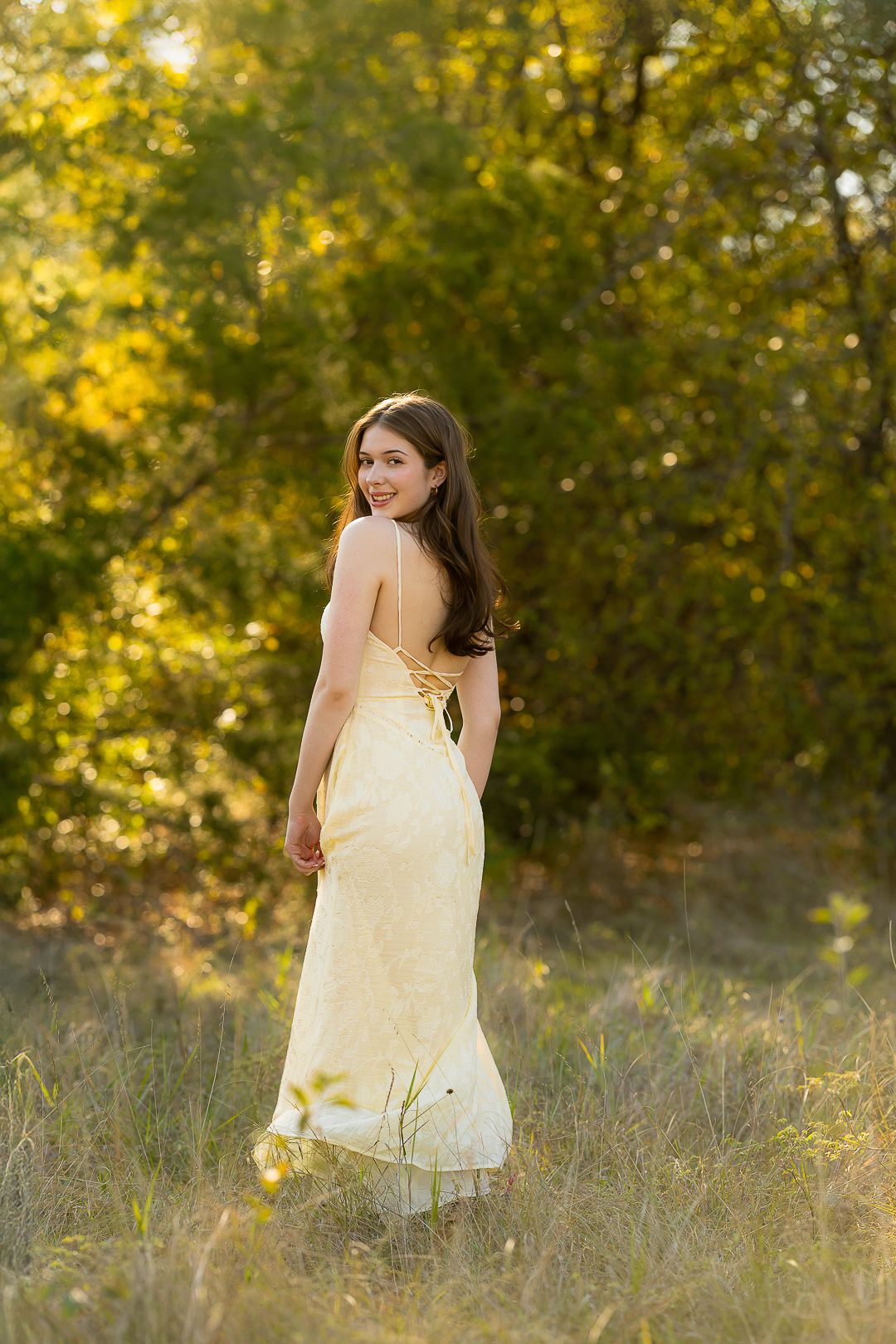 Yellow sundress photoshoot in a sunlit meadow with golden wildflowers.